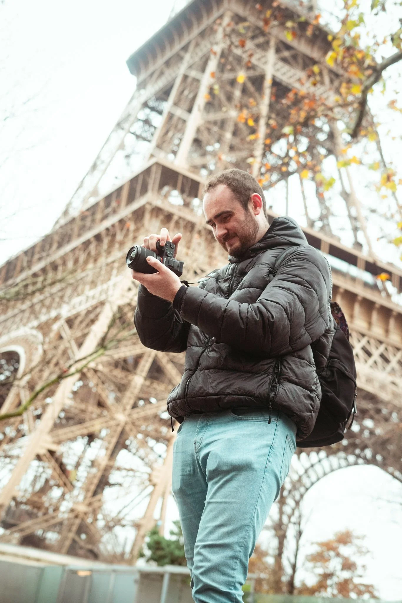 Person holding a camera with the Eiffel Tower in the background.