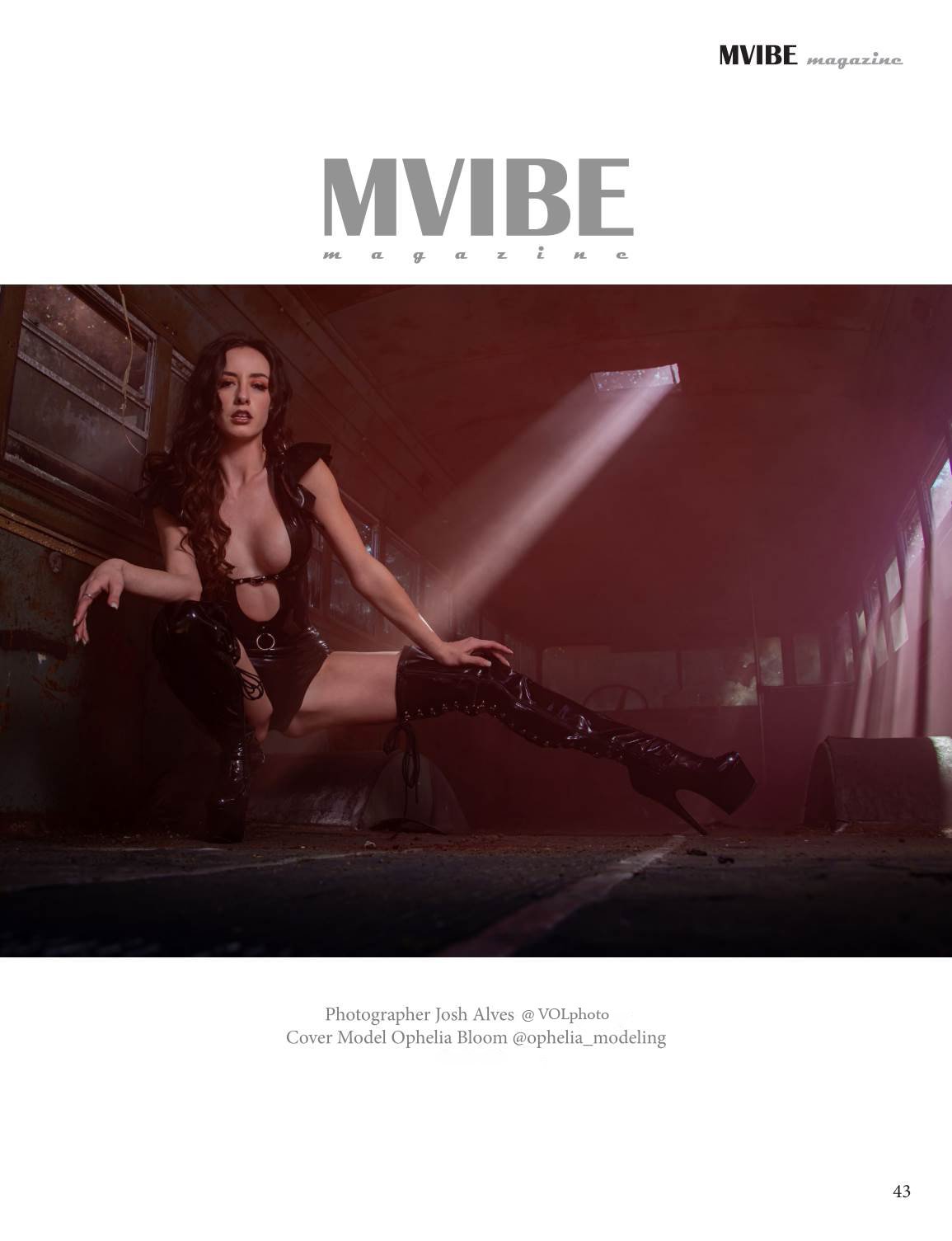 A woman wearing black PVC clothing and high-heeled boots poses on a dark, industrial-style room with sunlight streaming through windows with the heading reading "MVIBE".