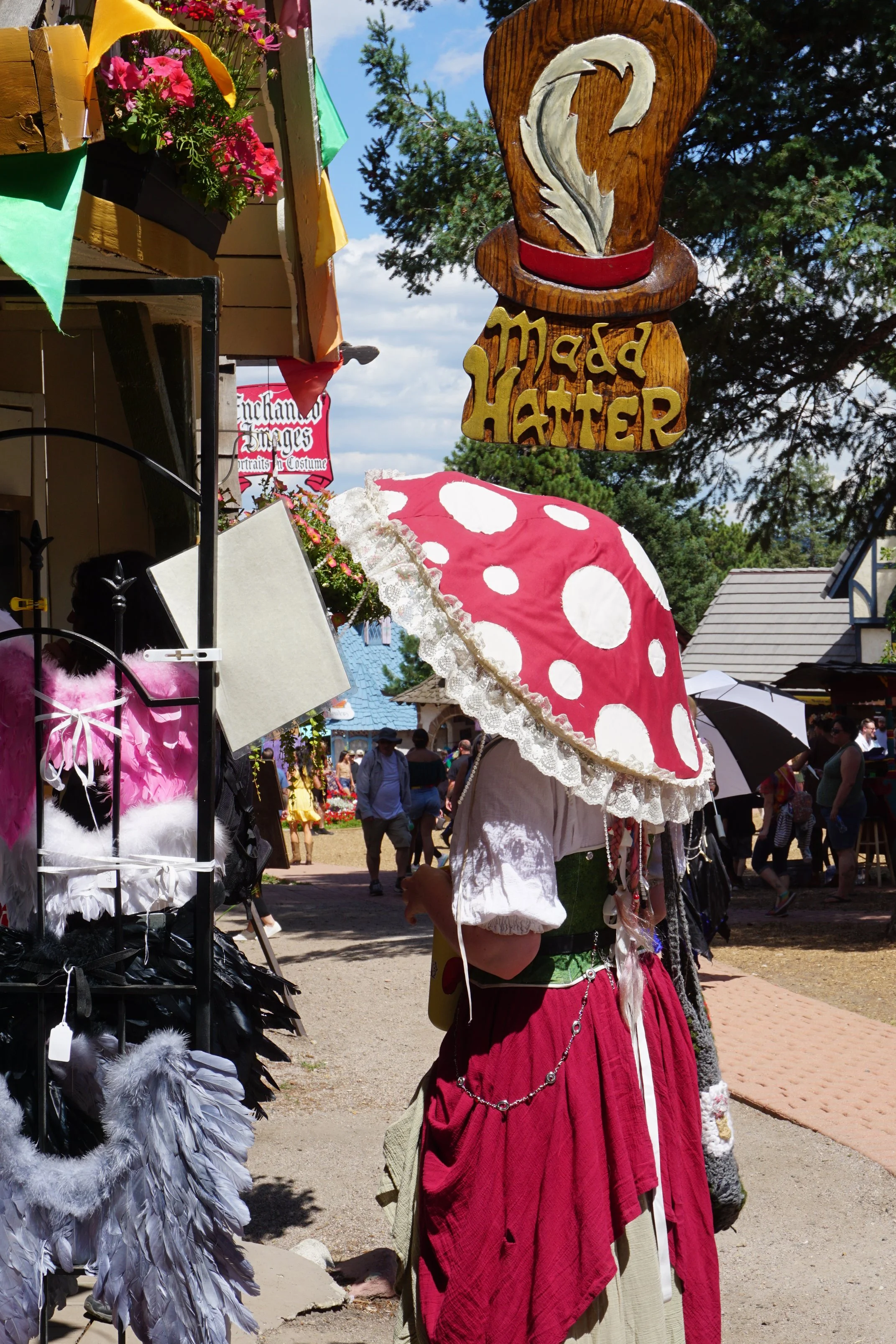 A woman stands underneath the Mad Hatter's shop at the Colorado Renaissance Festival in Larkspur, Colo., on Saturday, Aug. 5, 2023. At the festival, many people dress up in renaissance-based outfits while adding a fantasy element with hats such as th