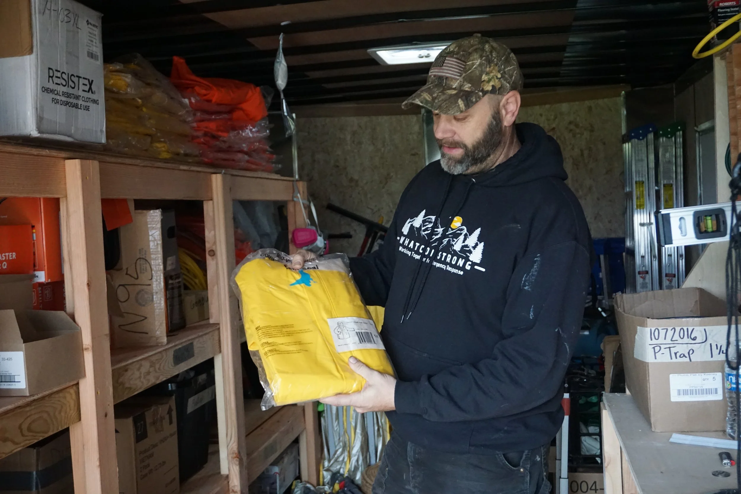 Kyle Christensen holds a jacket for volunteers worn during dispatches to people's homes at the Sumas Advent Church in Sumas, Wash., on Jan. 29, 2026. Volunteers at WLTRG would wear these during their dispatches to help remove flood debris and take o