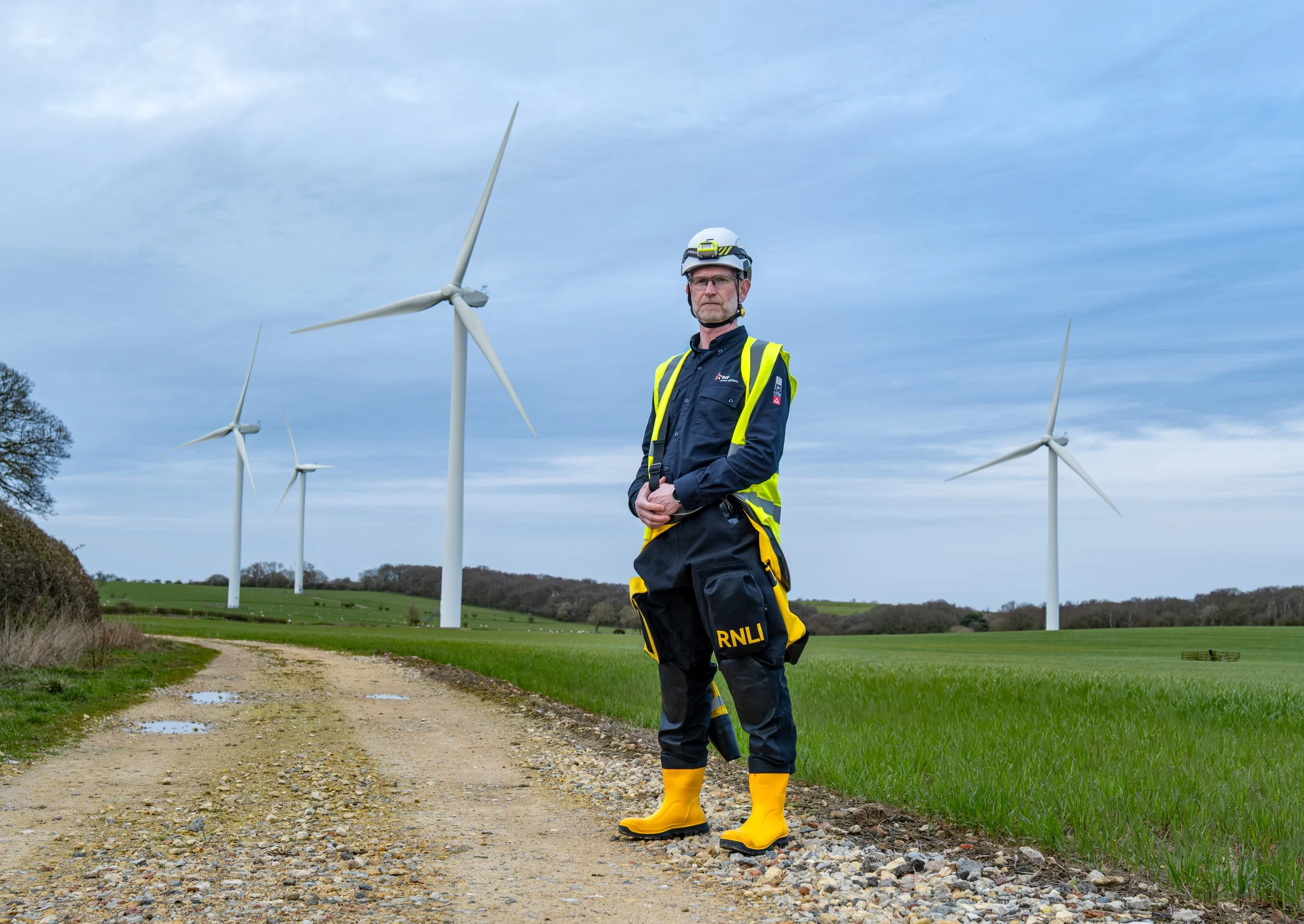 Environmental portrait of an RNLI volunteer photographed in front of wind turbines in the North East of England, part of a documentary photography project exploring the people behind the RNLI.