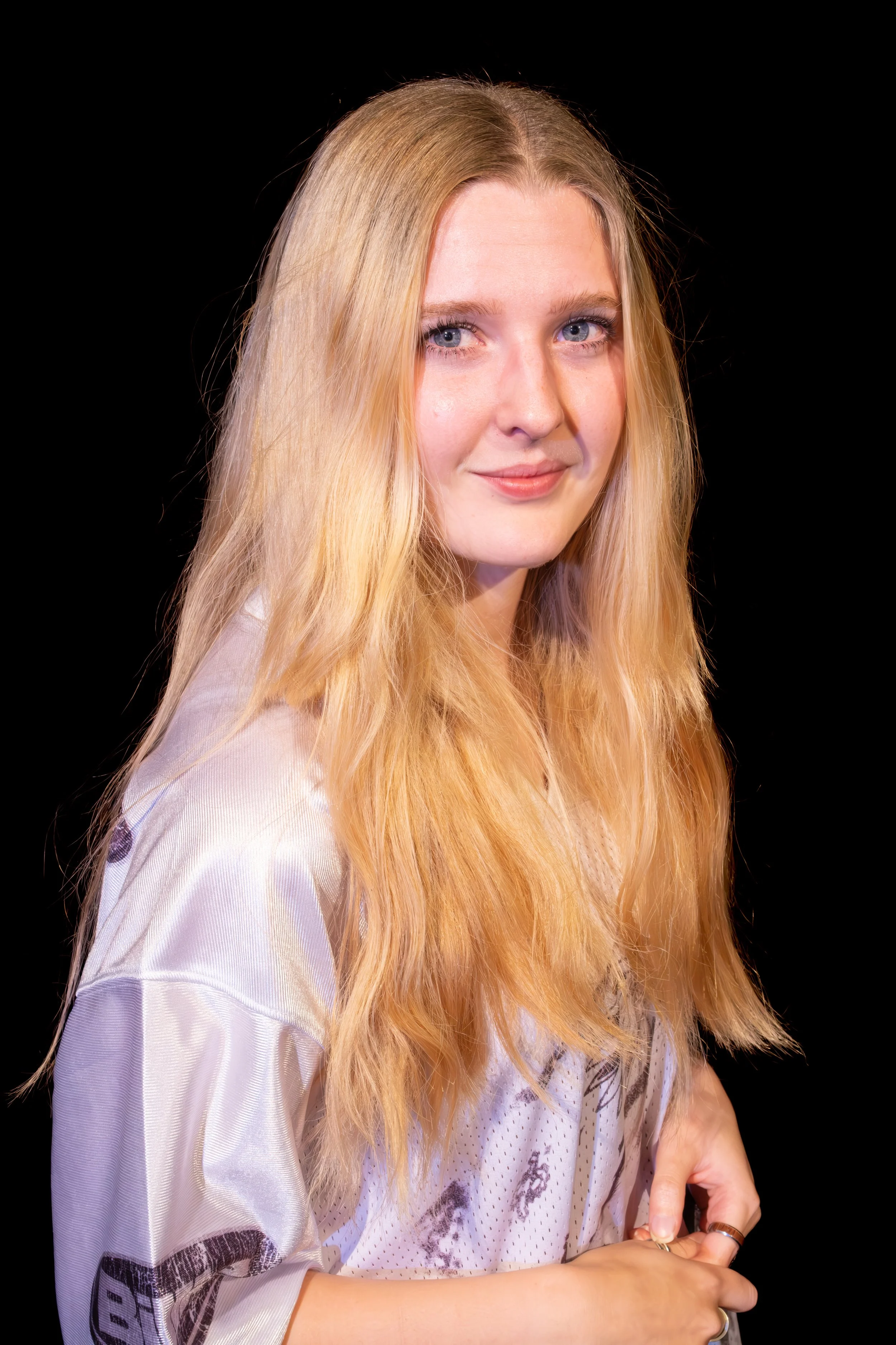 Studio headshot of a young woman photographed against a black background.