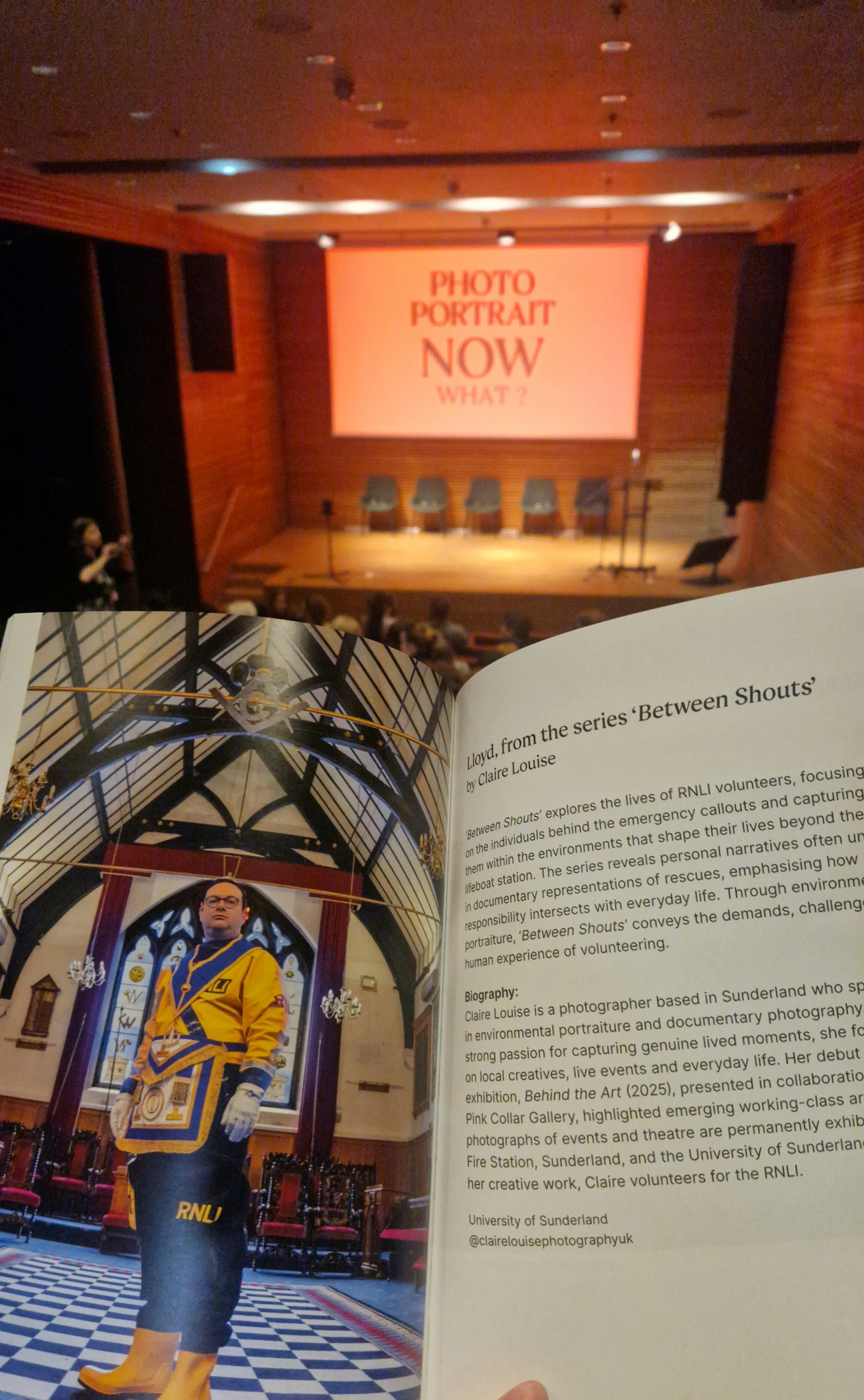 Open book showing a profile image of a woman in a yellow and blue RNLI-themed outfit standing in an ornate room with stained glass windows and chandeliers, and a page of printed text about Claire Louise, a photographer.