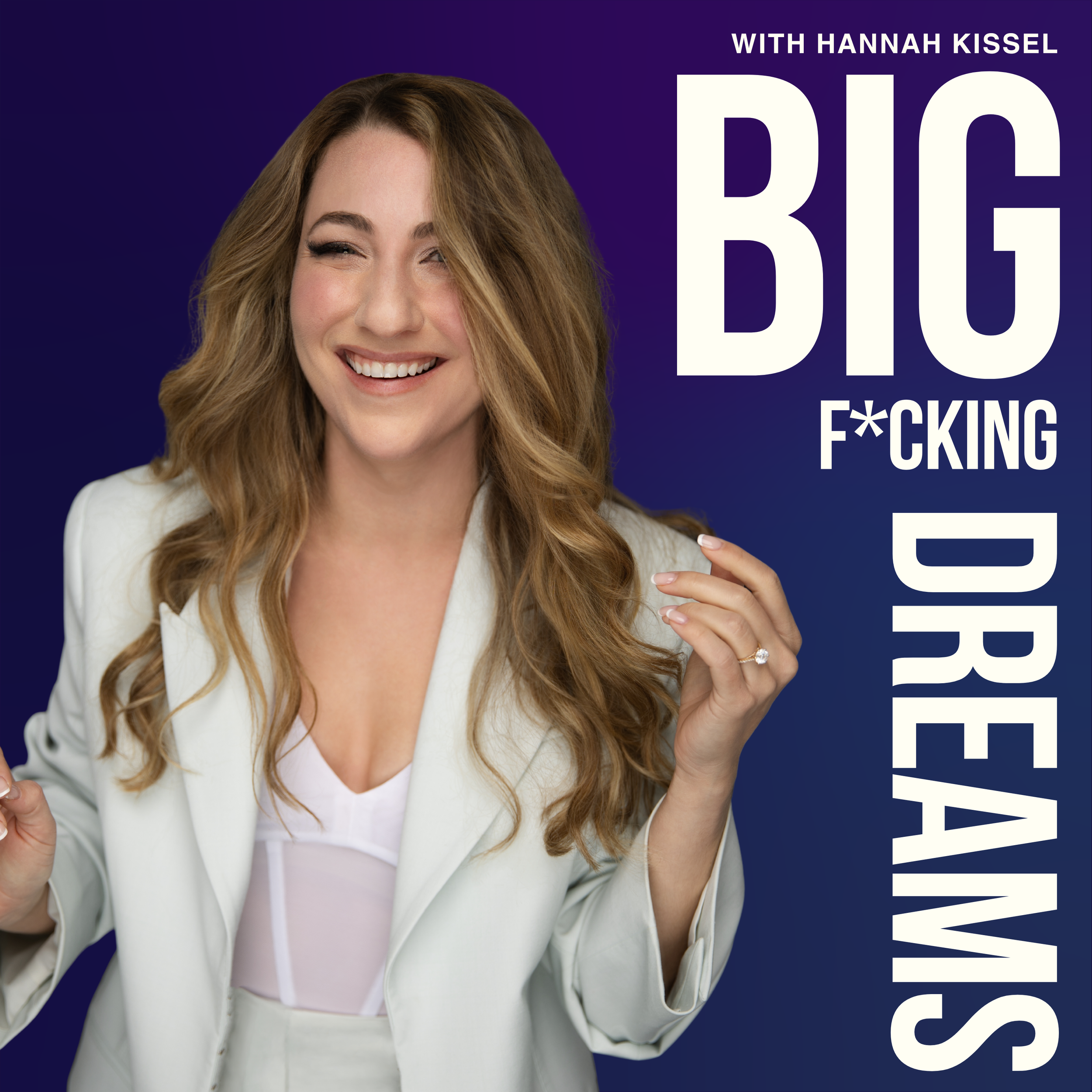 A woman smiling with long, wavy, light brown hair, wearing a white blazer and a white top, standing against a dark blue background.