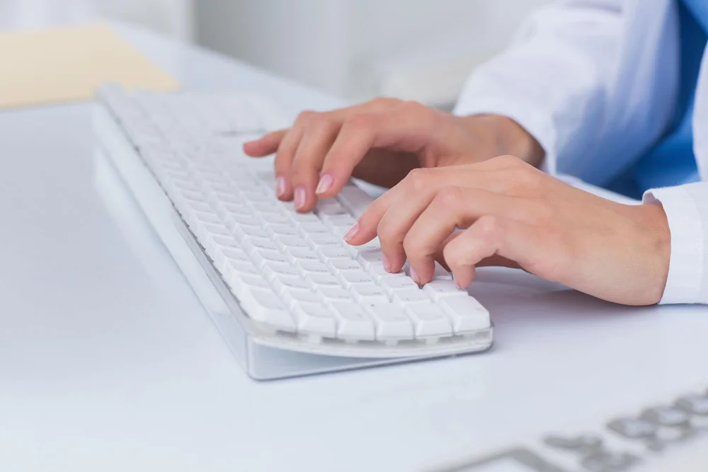 Hands typing a medical transcription