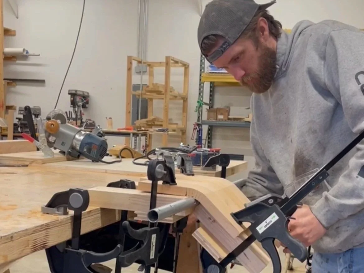 Woodworking in a workshop. Man bending quality wood for furniture using clamps