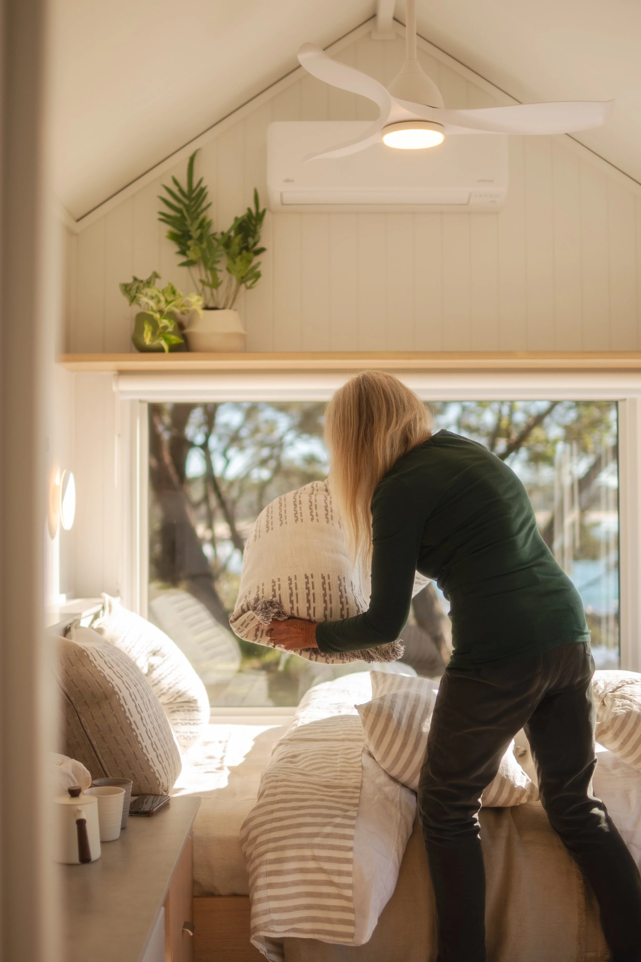woman making bed in a tiny home