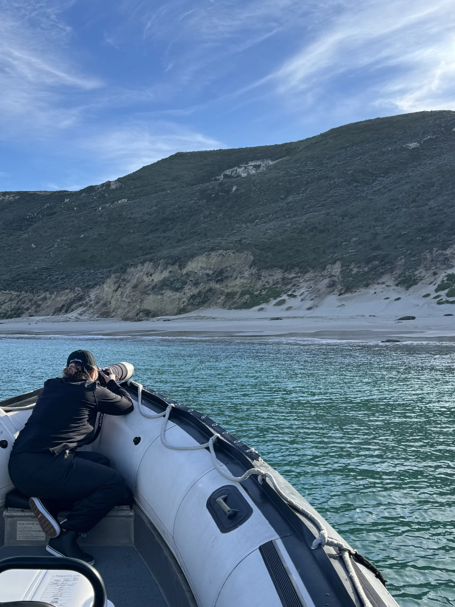 Alexis photographing elephant seals on a beach at San Miguel Island from the bow of a Zodiac, using a long telephoto lens.