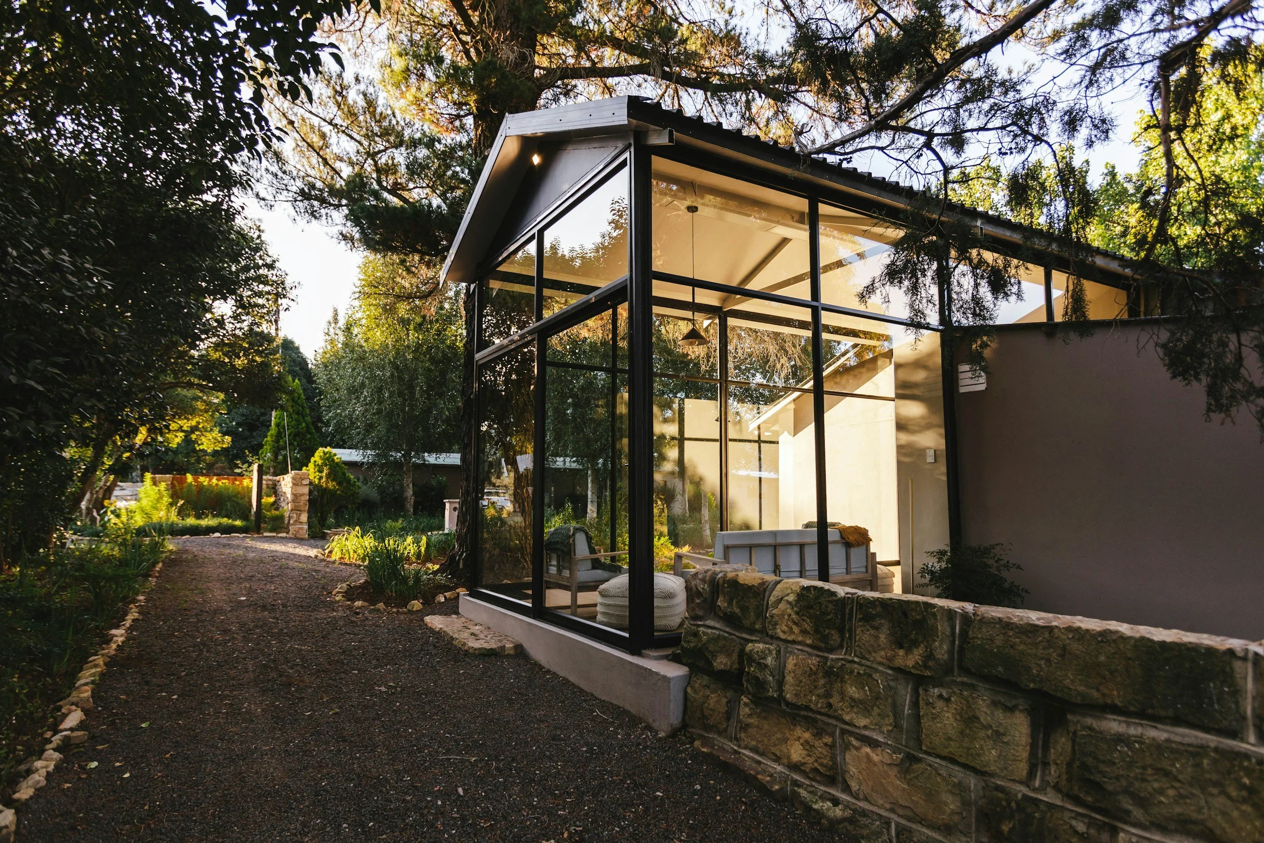 Glass pavilion structure surrounded by trees, representing sustainable design and energy efficiency.