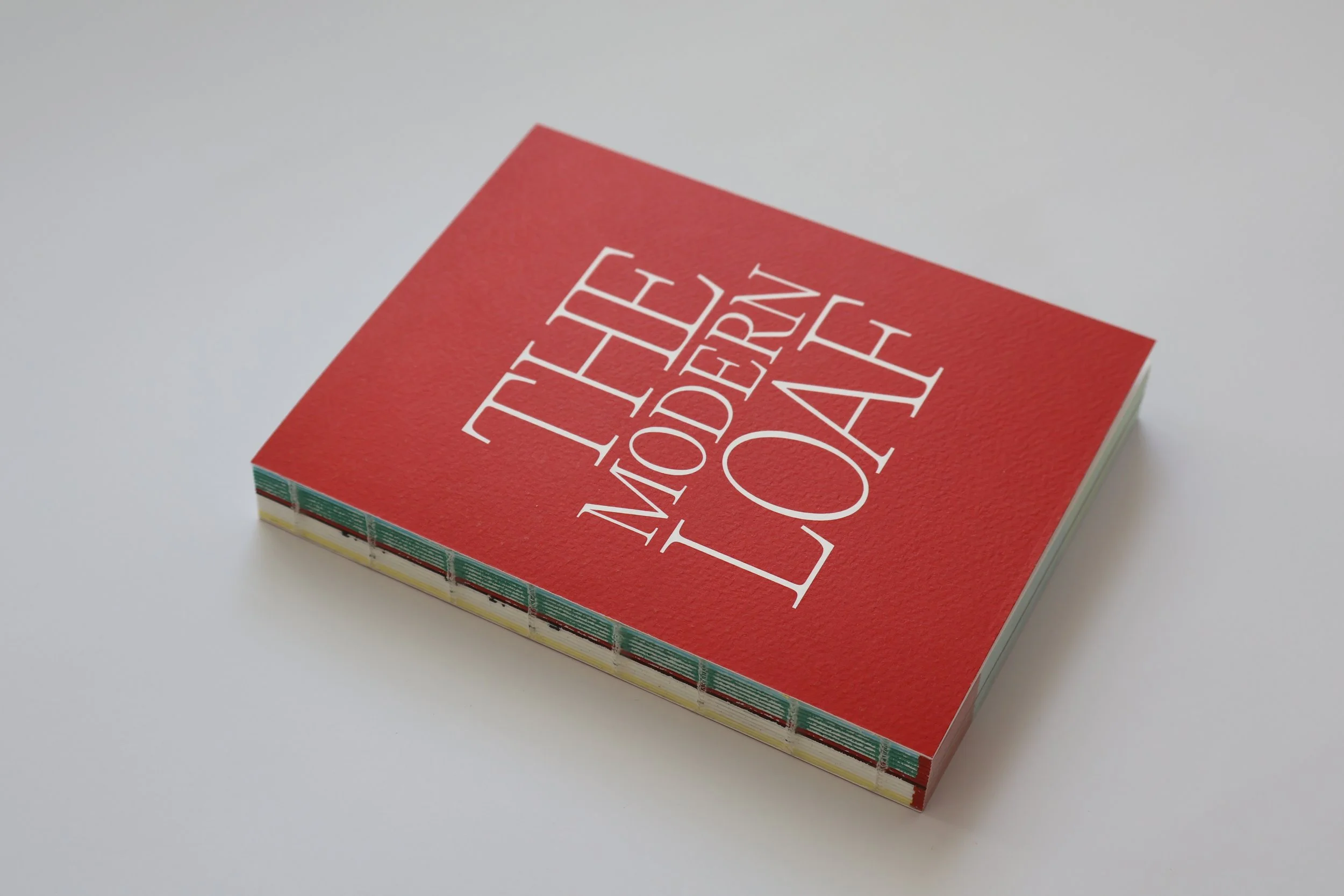 Red book titled 'THE MODERN LOAF' on a white surface, with a unique colorful external binding.