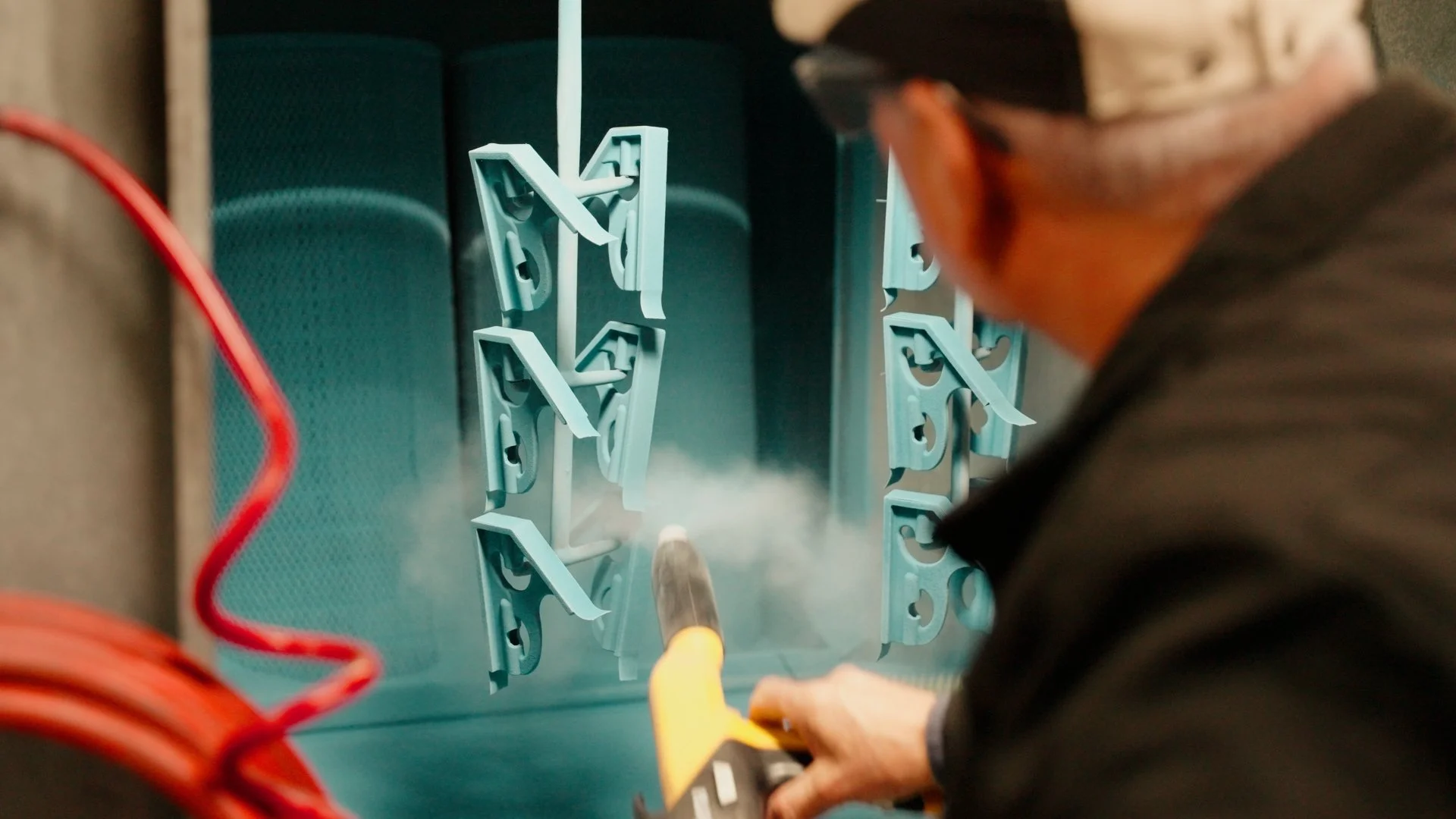 Person using a heat gun to work on a metal structure inside an industrial or workshop setting.
