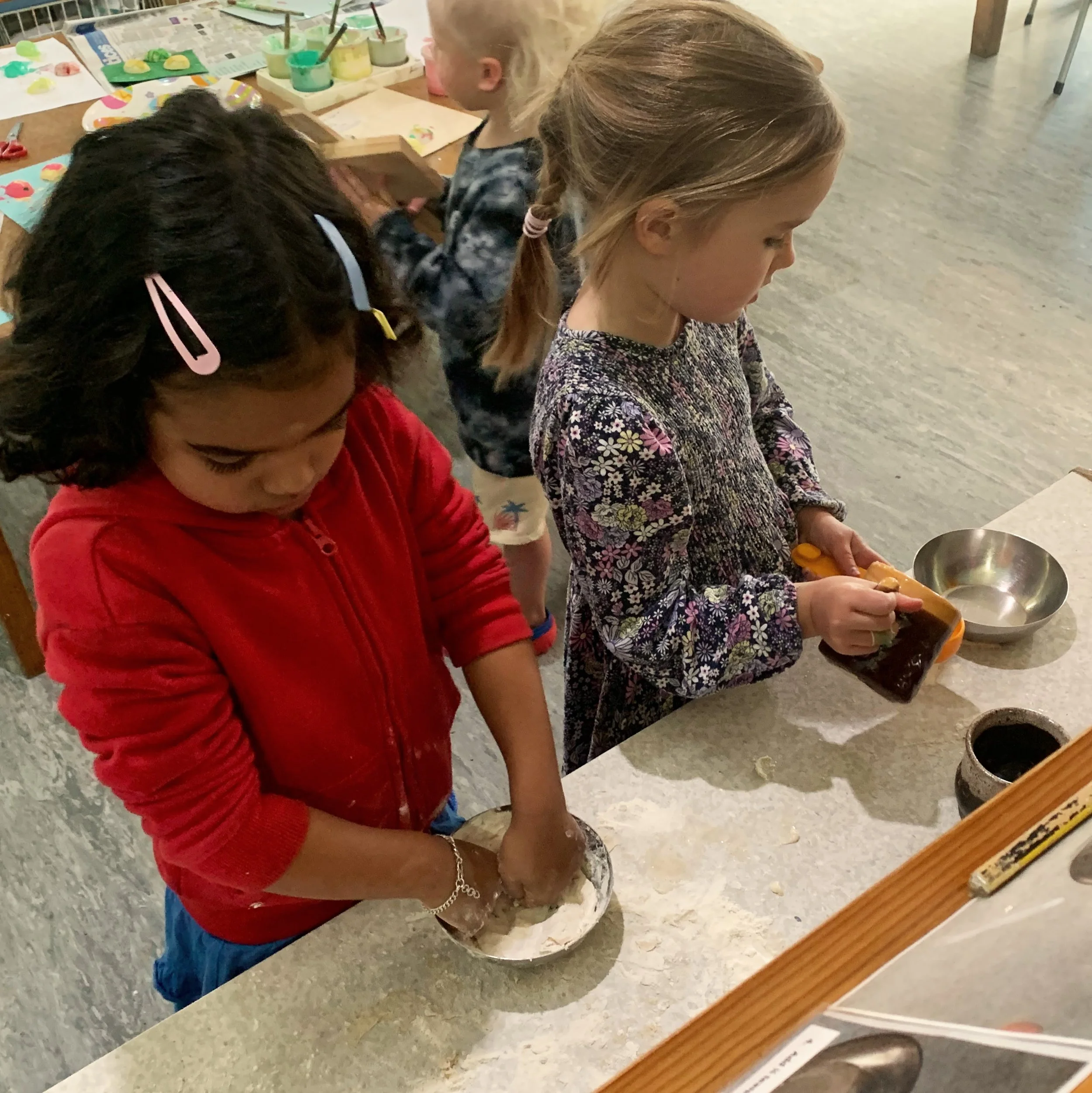 Two young girls are baking at the baking bench.