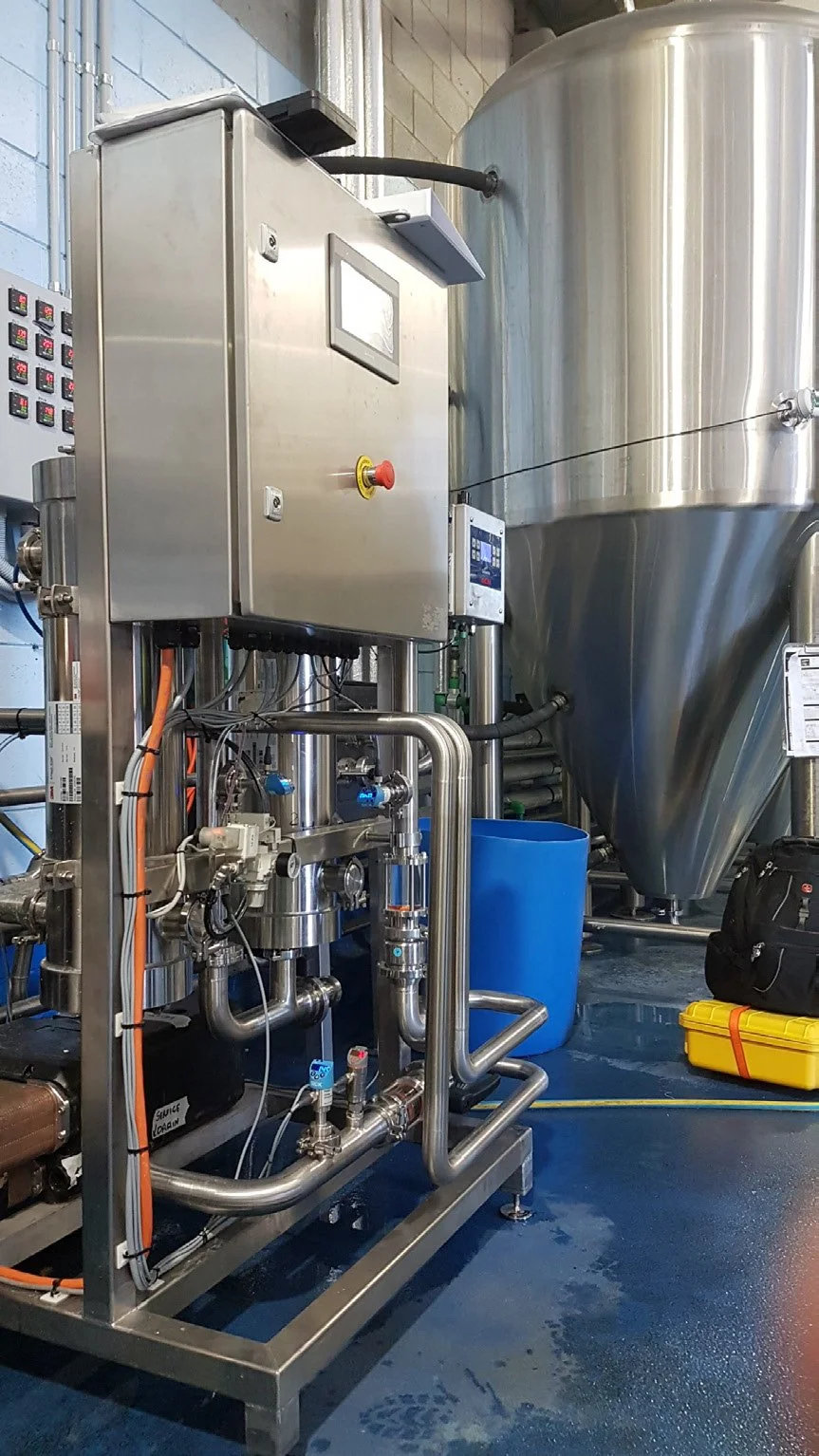 Industrial brewing equipment with stainless steel tanks and control panel in a brewery.