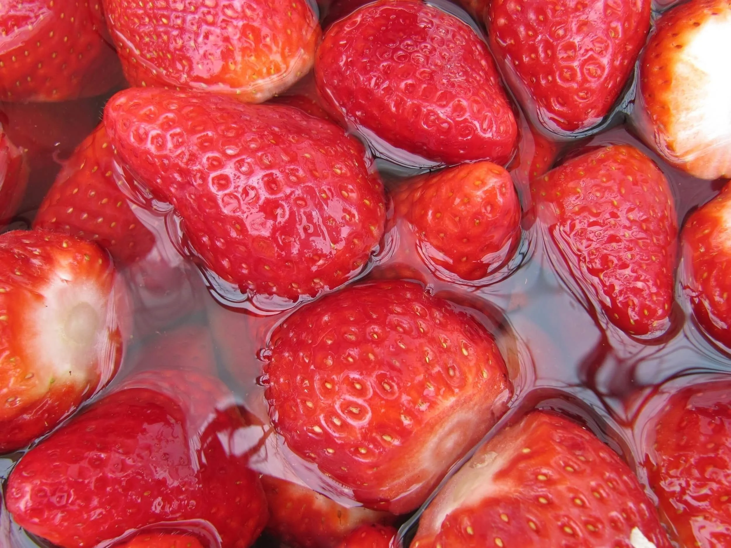 Close-up of fresh, ripe strawberries submerged in water.