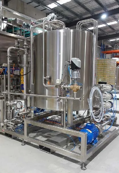 Industrial stainless steel tank with pipes and pumps in a manufacturing facility.