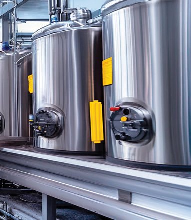 Stainless steel industrial fermentation tanks in a brewery or manufacturing facility.
