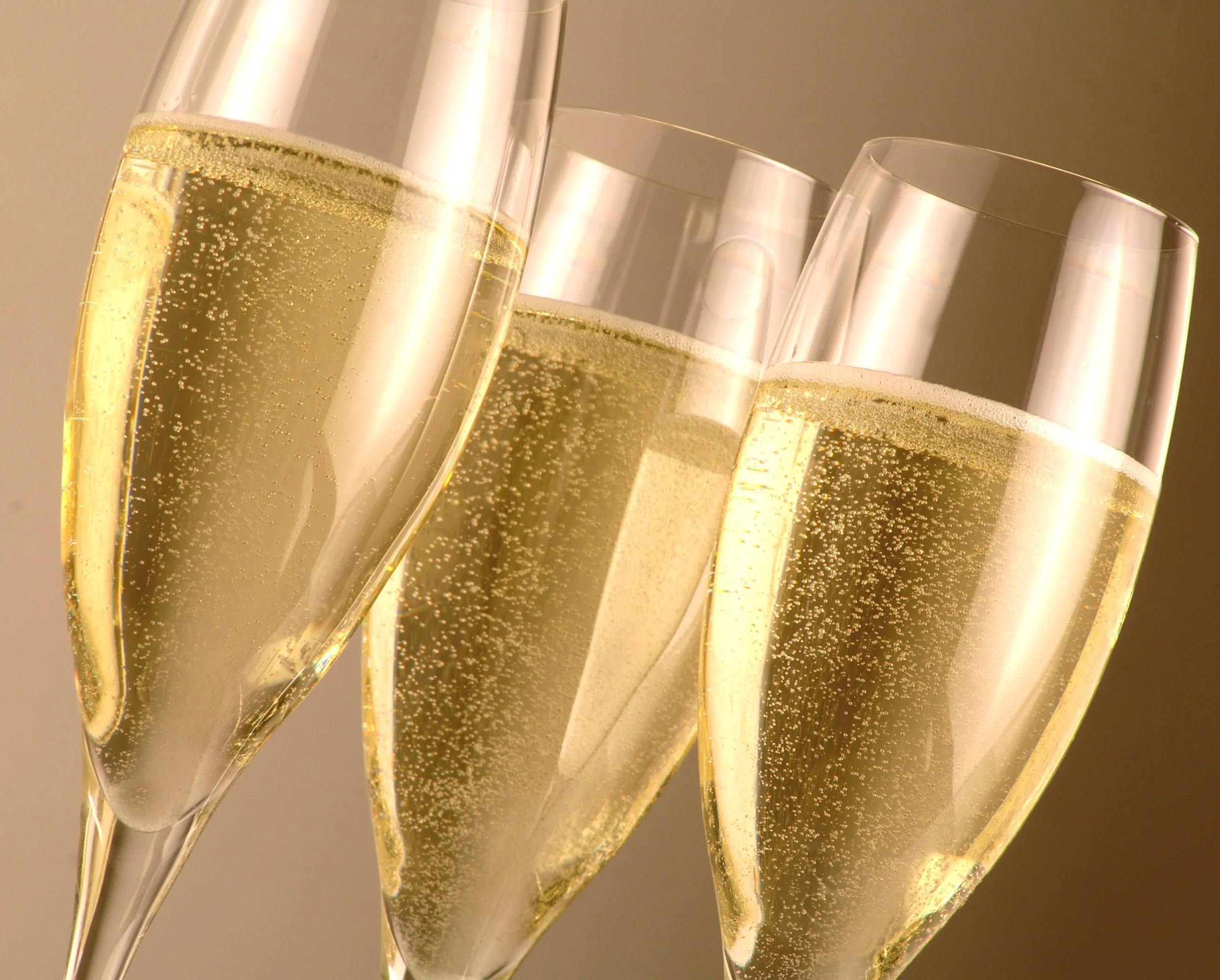 Three glasses of champagne clinking together, filled with bubbly champagne.