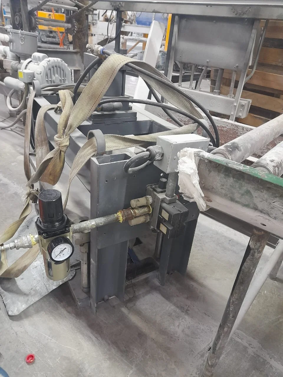 Maquinaria industrial en un taller de construcción, con tubos, cintas y componentes metálicos.
