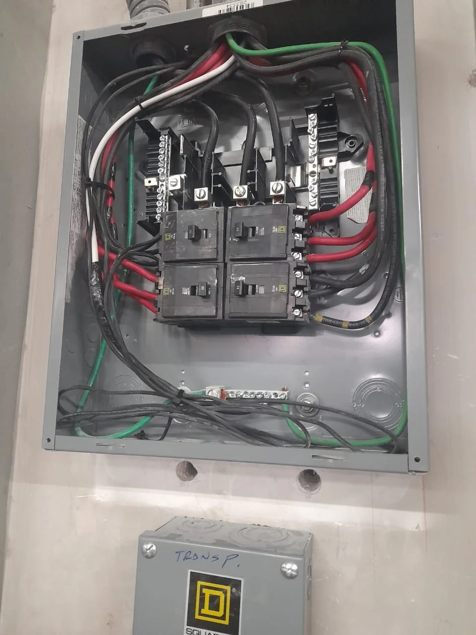 Tablero de caja eléctrica abierto con componentes internos, cables y interruptores visibles.
