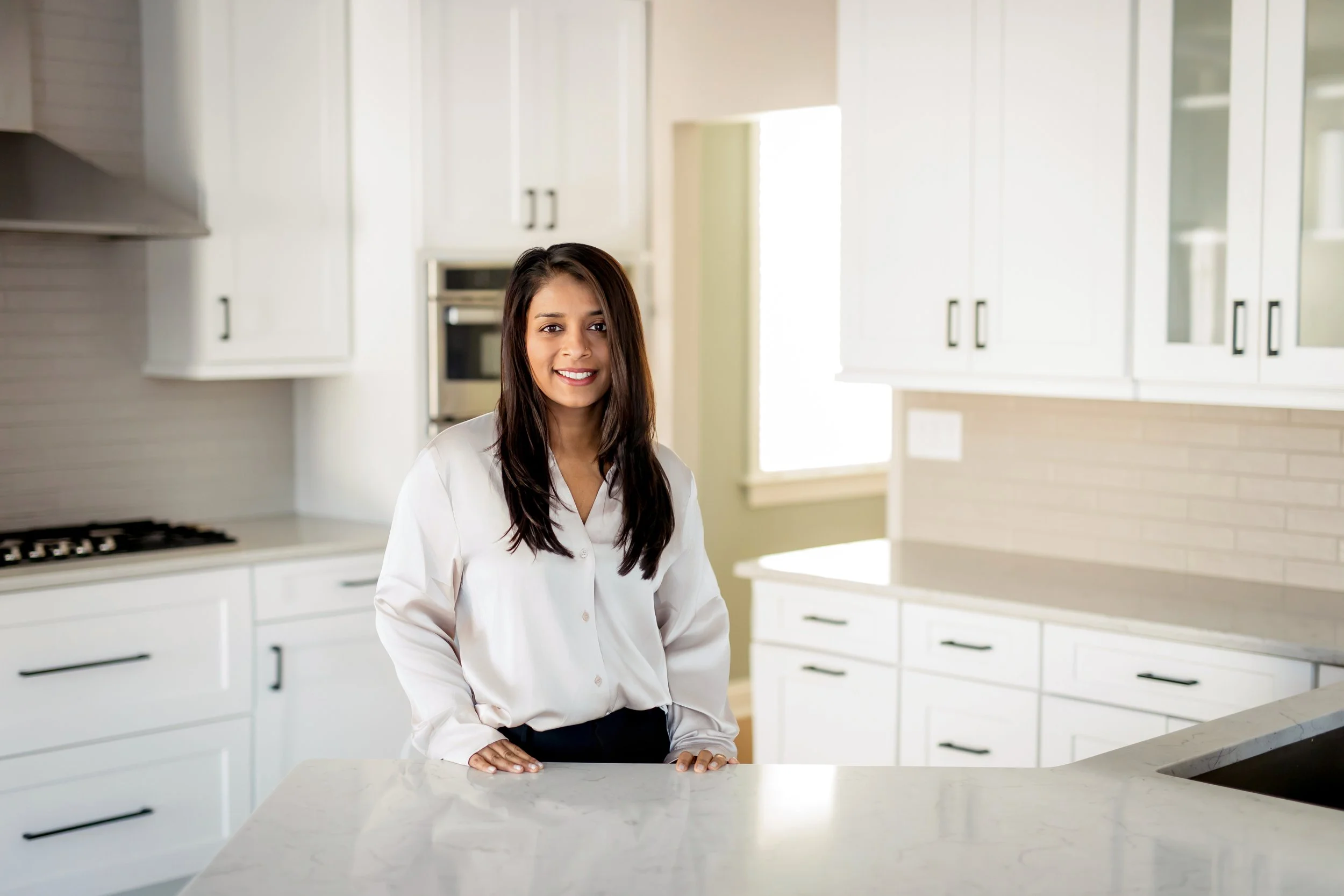 Dr. Swetha Voddi in a stylish kitchen with white cabinets and a marble countertop