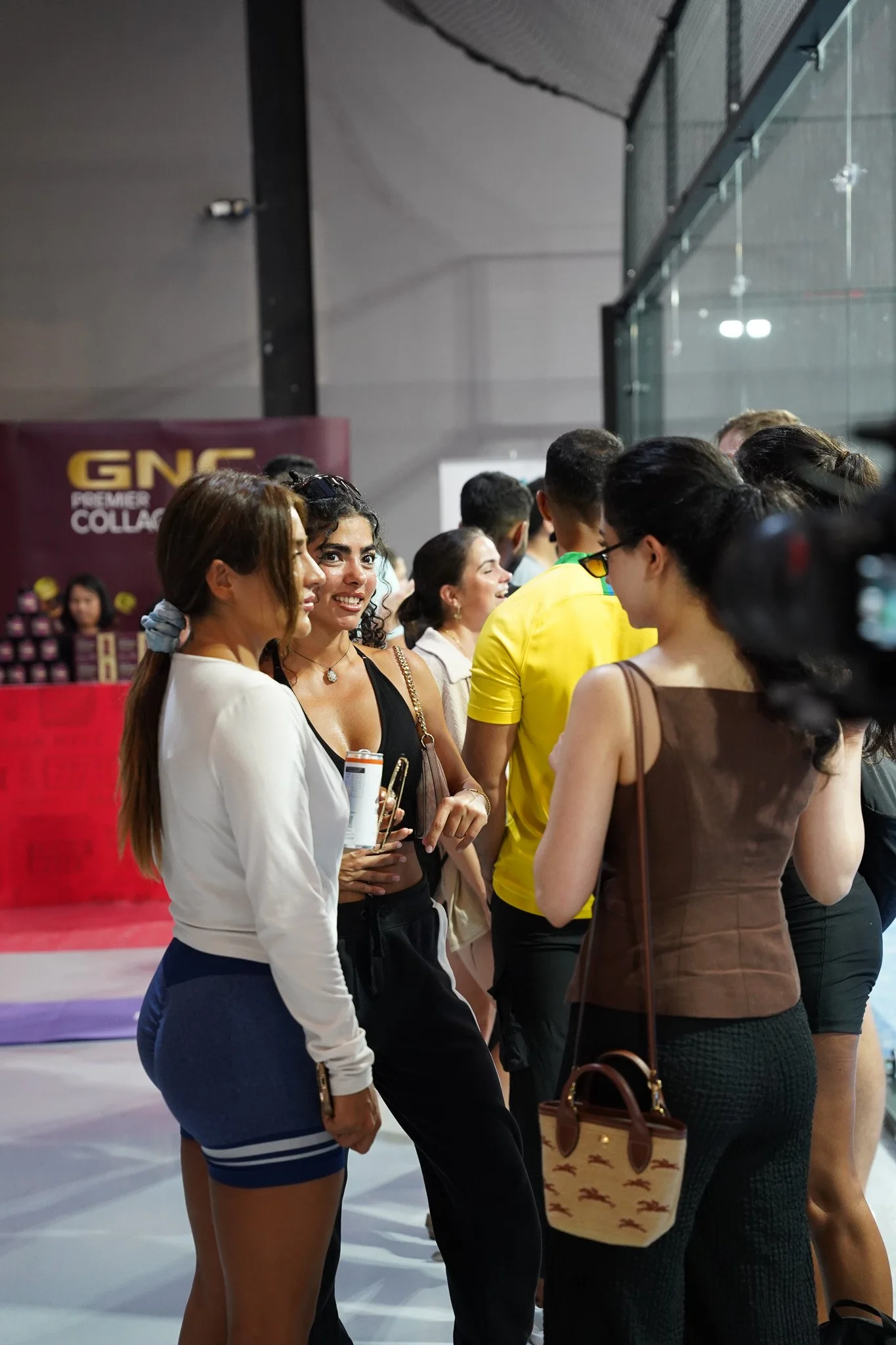 Group of people standing in line at an event, with a woman in the center smiling and holding a can.