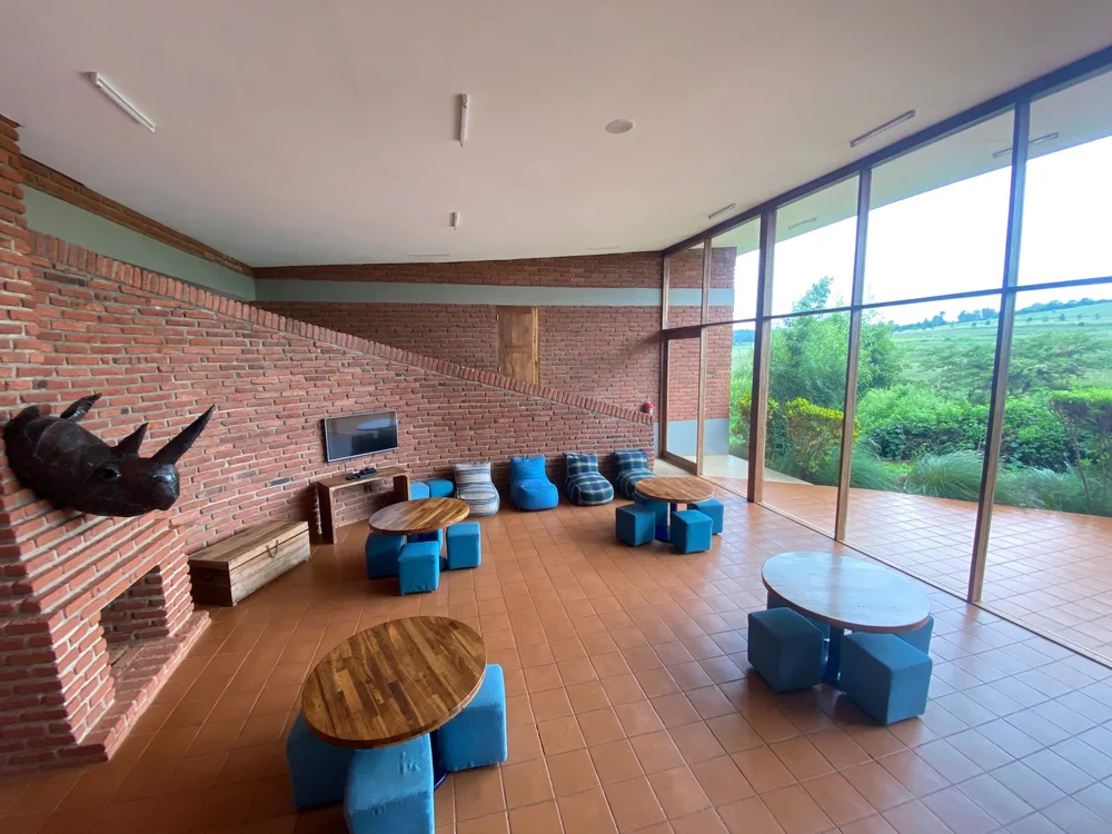 Boarding common room with blue seating, wooden tables and floor-to-ceiling windows looking out over green fields