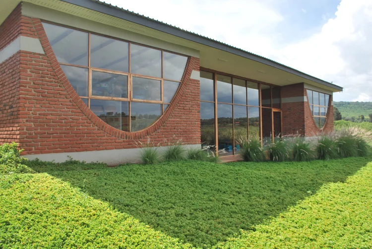 Brick boarding house with large arched windows surrounded by green lawn