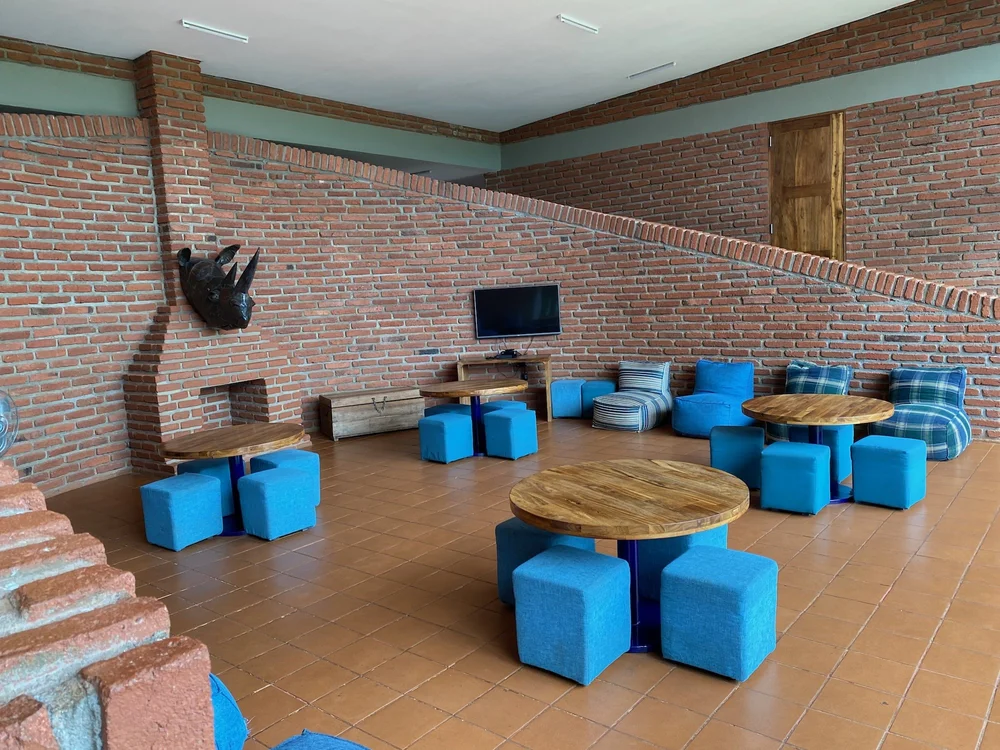 Shared living room with a fireplace, a TV, and blue cube seats around wooden tables