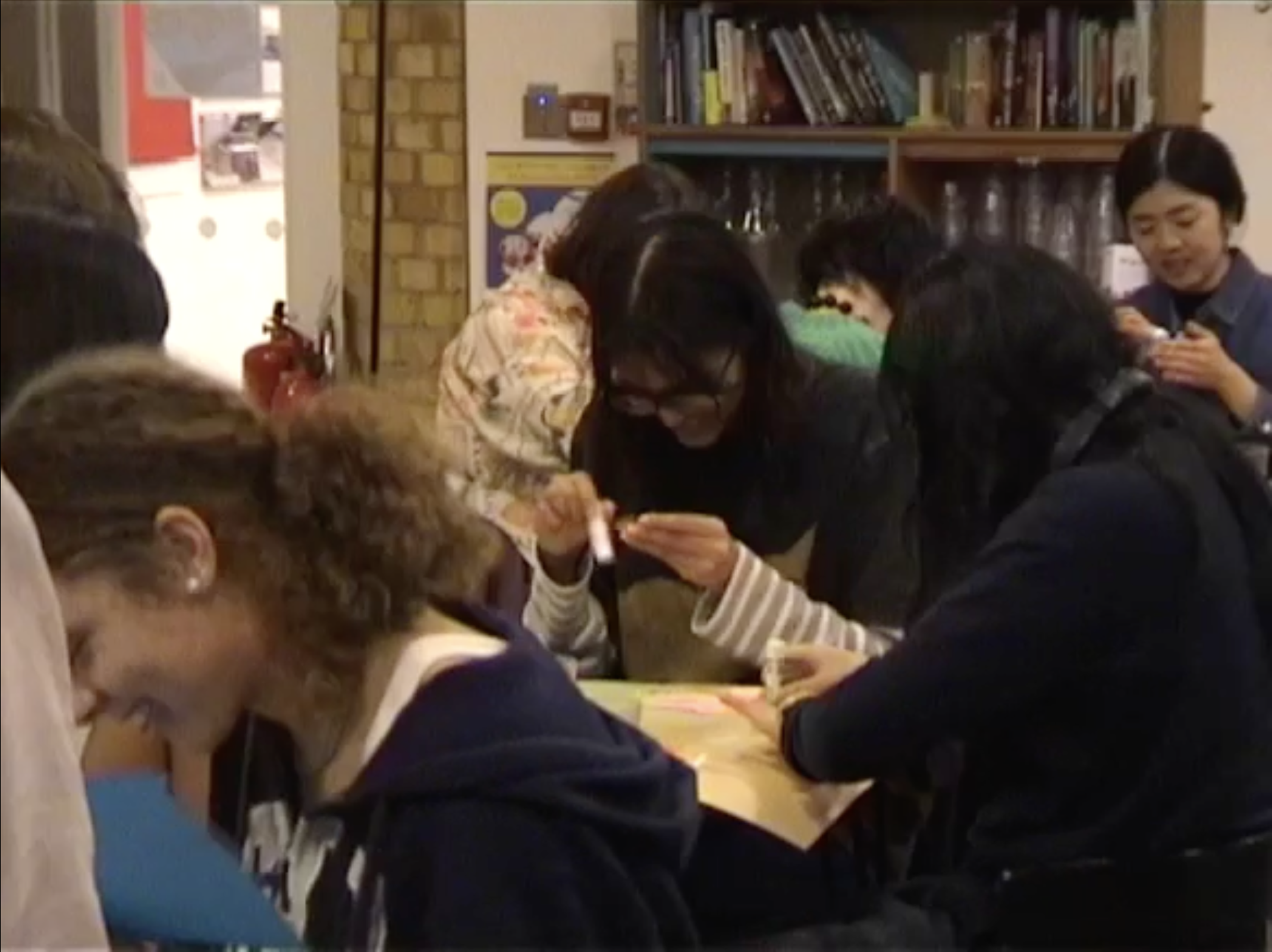 Group of people with their heads down drawing, all with big smiles.