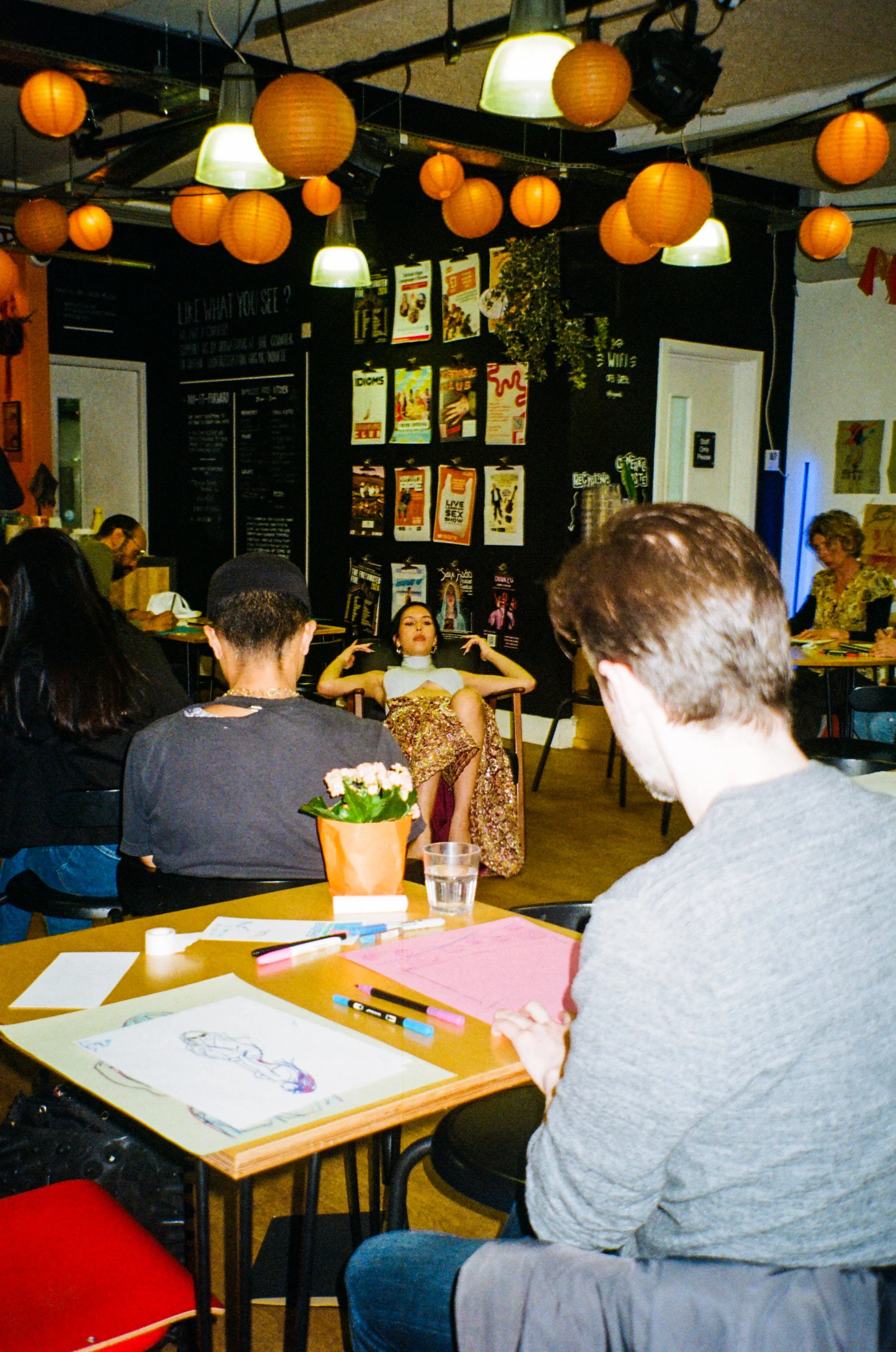 Reclining fashion illustration model surrounded by people drawing