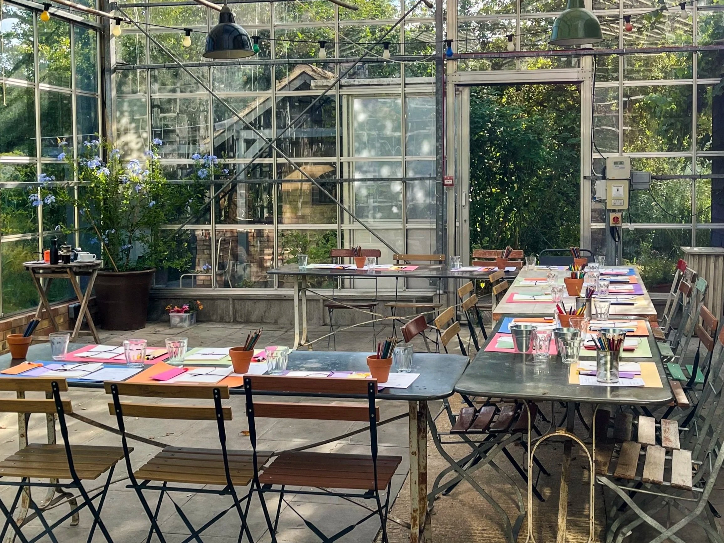 Tables set in horse-shoe layout within glasshouse space at Worton Kitchen Garden.