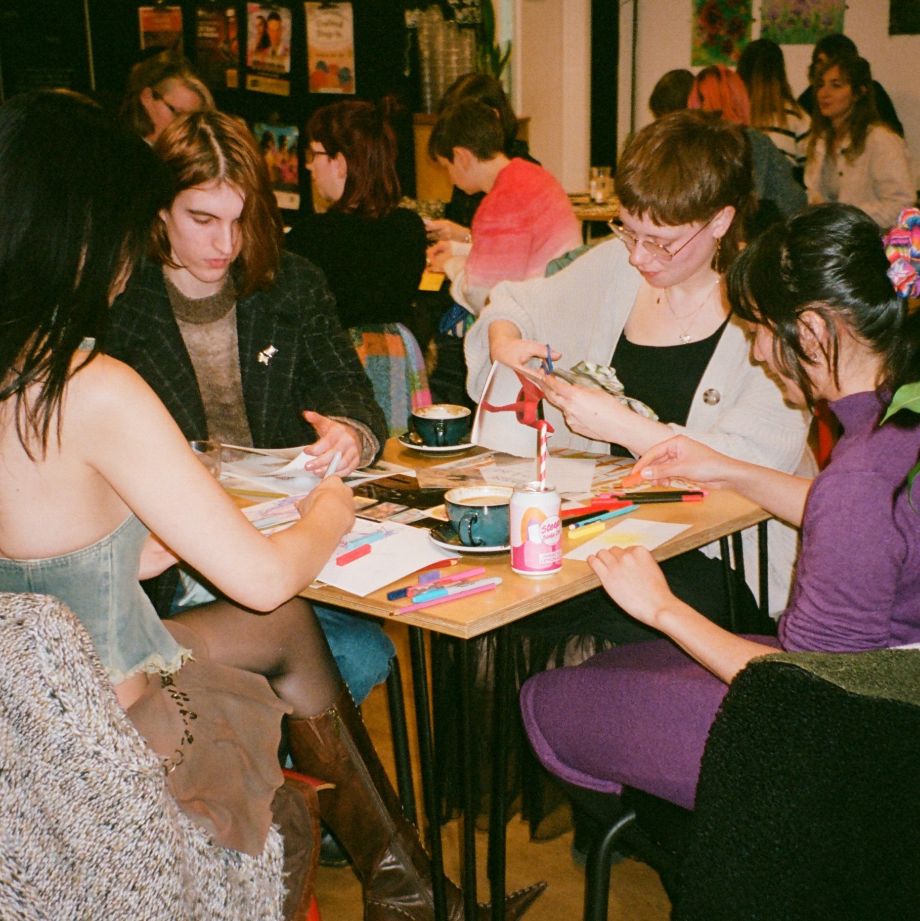 Four people sat creating around a small square table. 