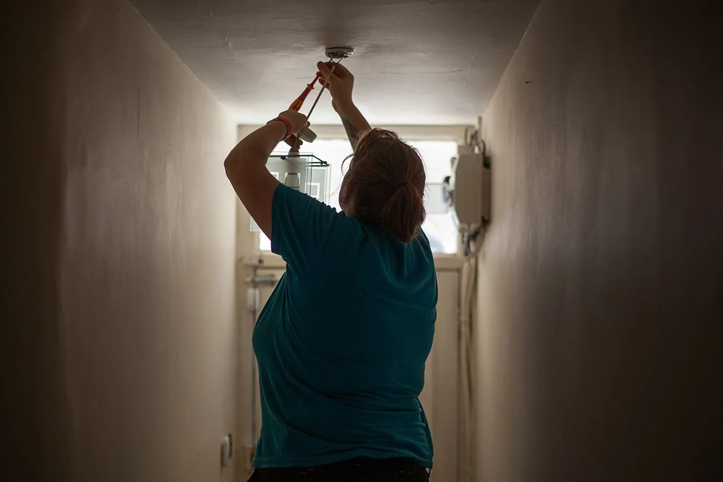 Checkatrade work. Anne, an electrician, at work at a domestic property. Wimbledon. 2025.