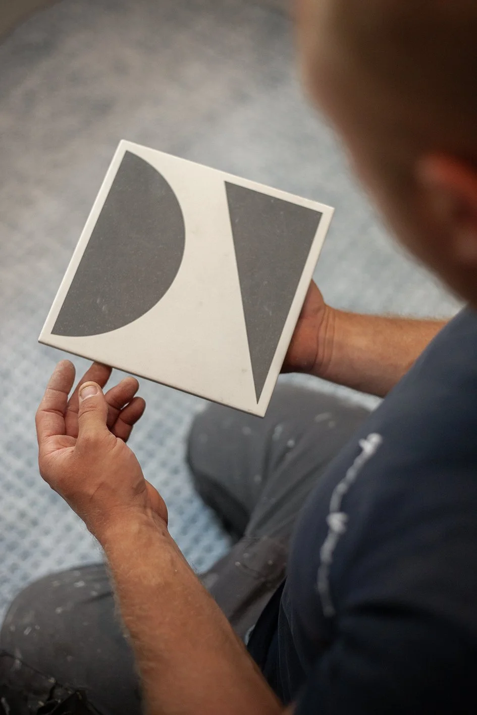 Checkatrade work. Harringay, London. Tomazs, at work as a bathroom renovator. Tomazs examines a bathroom tile before installation. 2025.