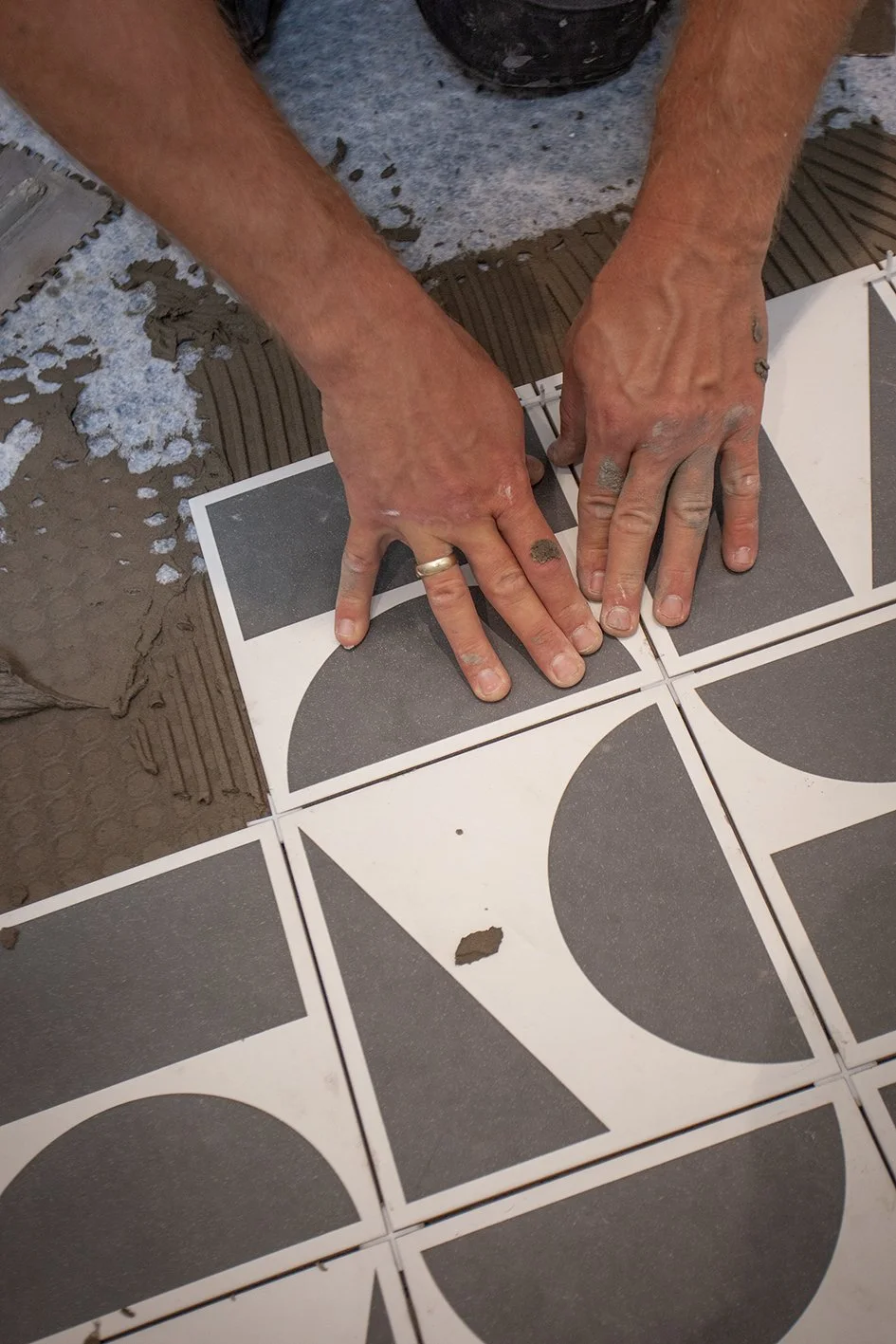 Checkatrade work. Harringay, London. Tomazs, at work as a bathroom renovator. Installing bathroom floor tiles. 2025.