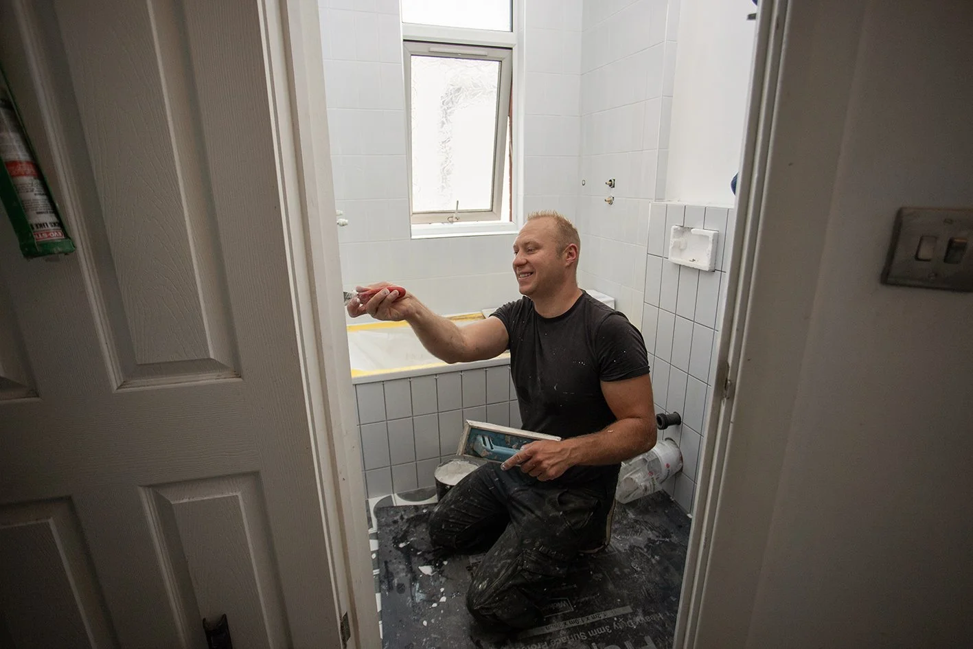 Checkatrade work. Harringay, London. Tomazs, at work as a bathroom renovator. Installing wall tiles. 2025.