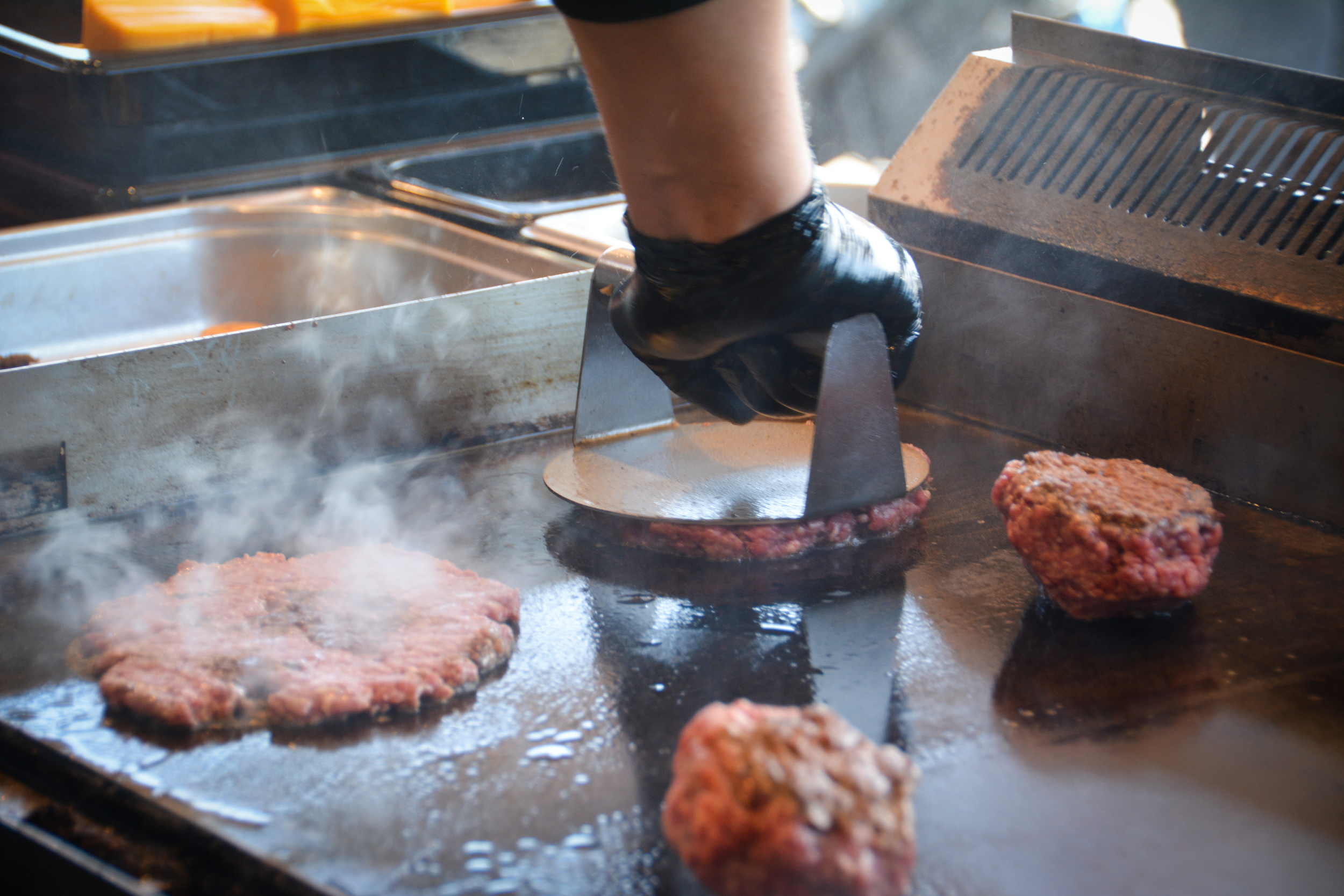 En person laver burgerbøf på en grill med kød, der bliver stegt │Smash Burger Truck│Copenhagen│ København