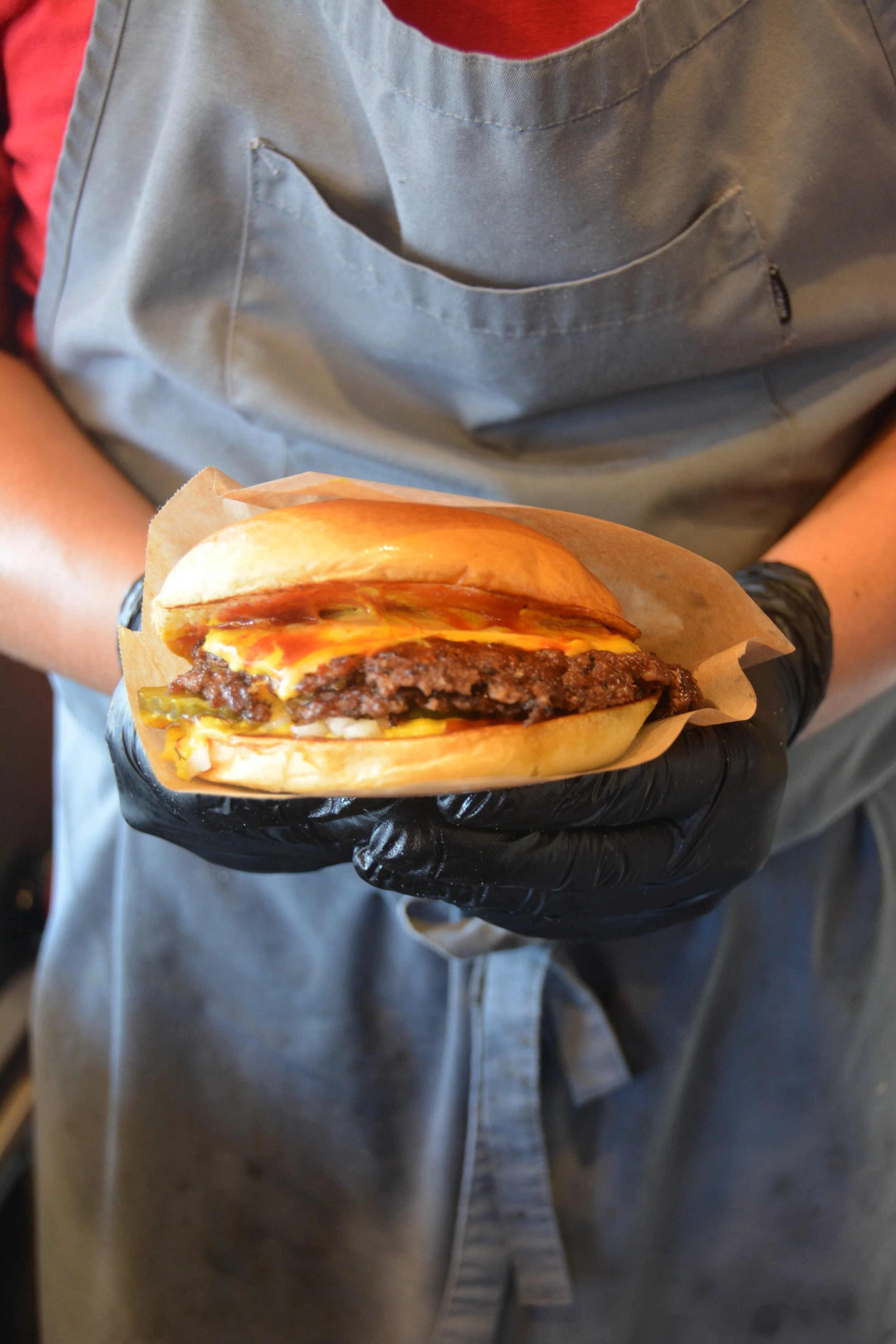 En person holder en hamburger med kød, ost, pickles og sauce, pakket ind i brød│Smash Burger Truck│Copenhagen│ København