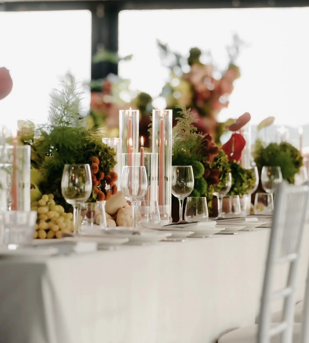 Decorative table setting with glassware, floral arrangements, and candles at an elegant event or wedding reception.