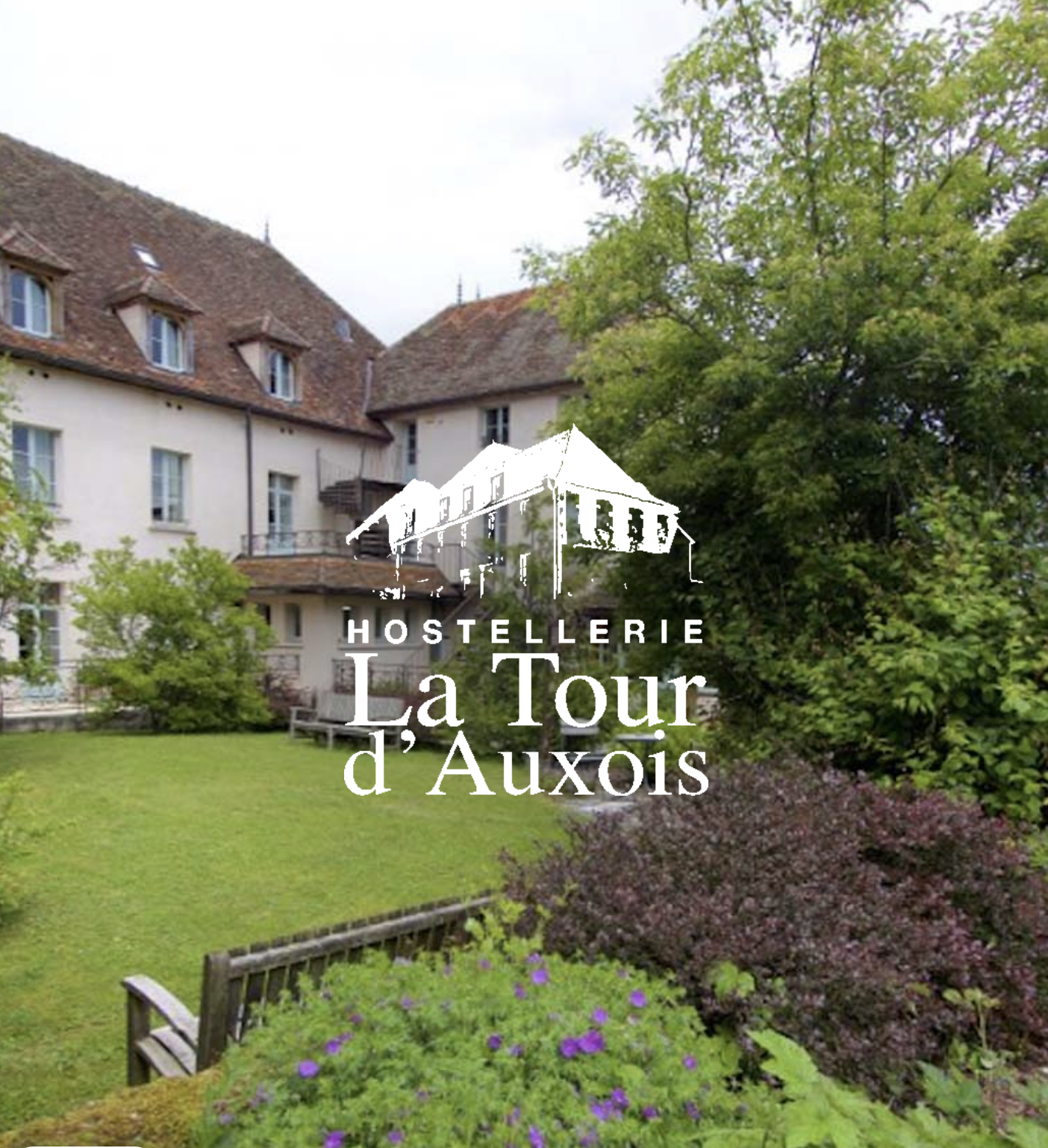 Vue d'un bâtiment ancien avec un toit en tuiles et des fenêtres, entouré d'un jardin vert avec des arbustes et des fleurs. En overlay, logo et texte "Hostellerie La Tour d'Auxois".