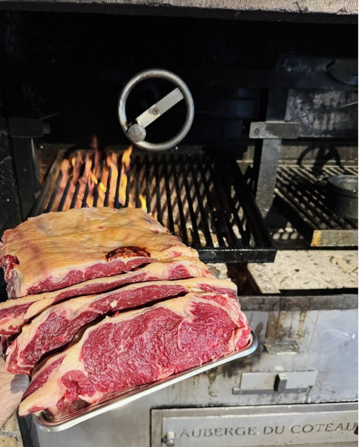Morceau de viande cru prêt à être grillé devant un barbecue à charbon de bois.