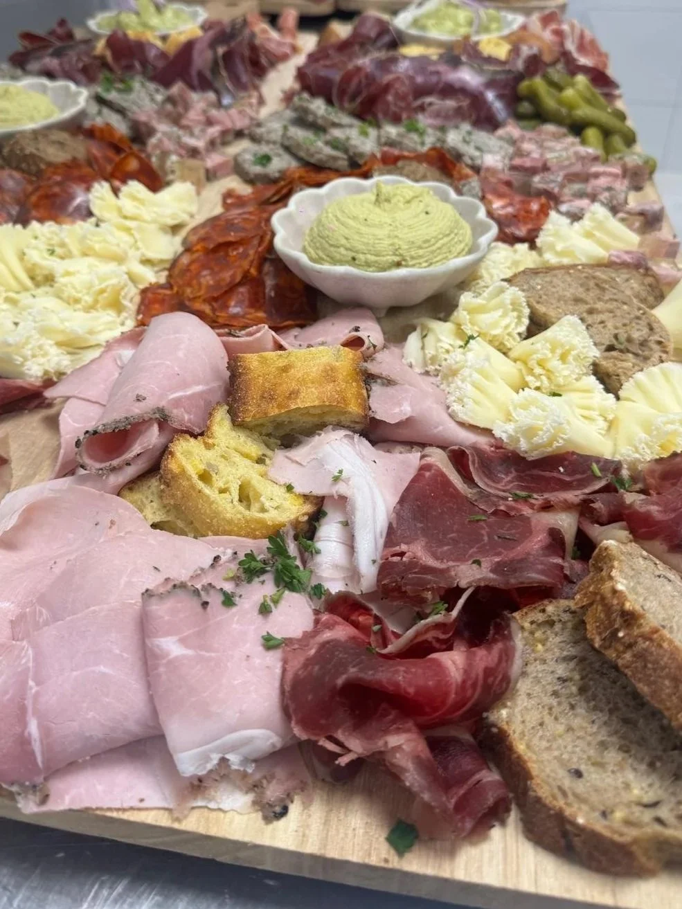Plate de charcuterie avec jambon, rosette, pâté, pain, fromage, beurre et guacamole.