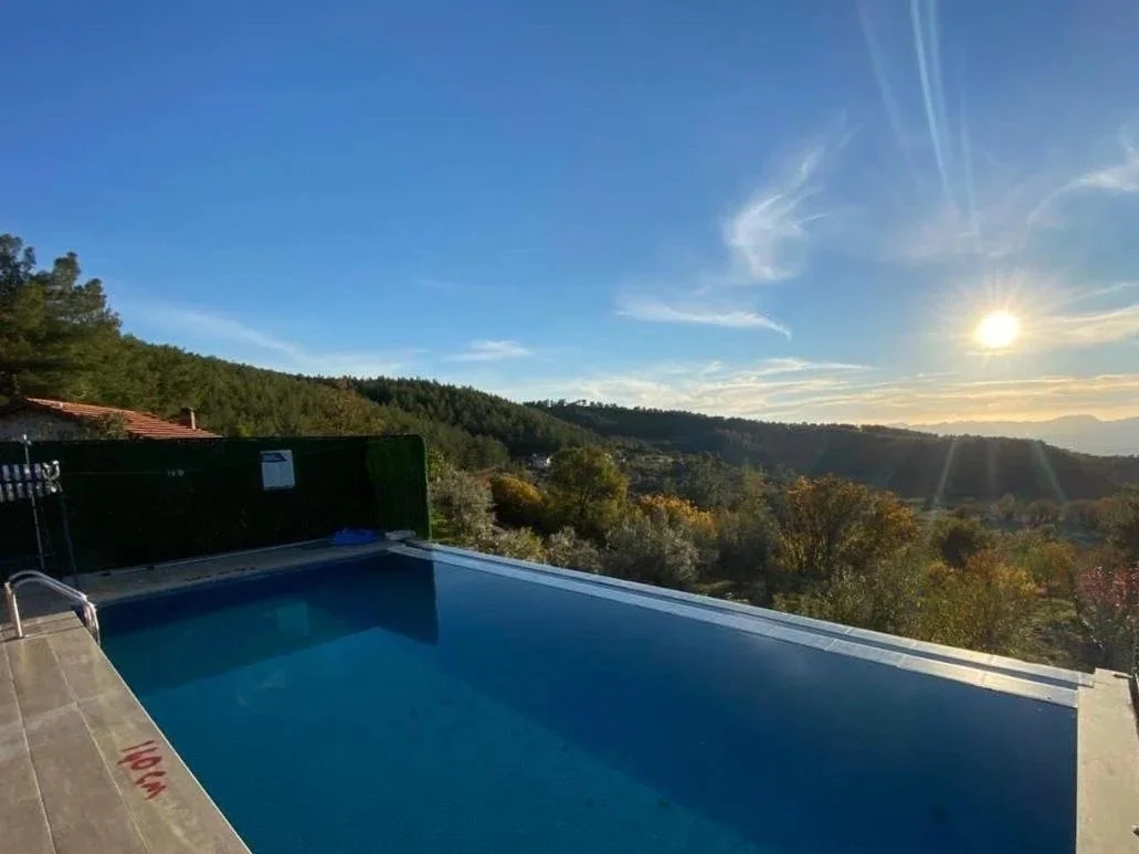 Infinity pool met een schilderachtig uitzicht op beboste heuvels en een felle zon aan de hemel.