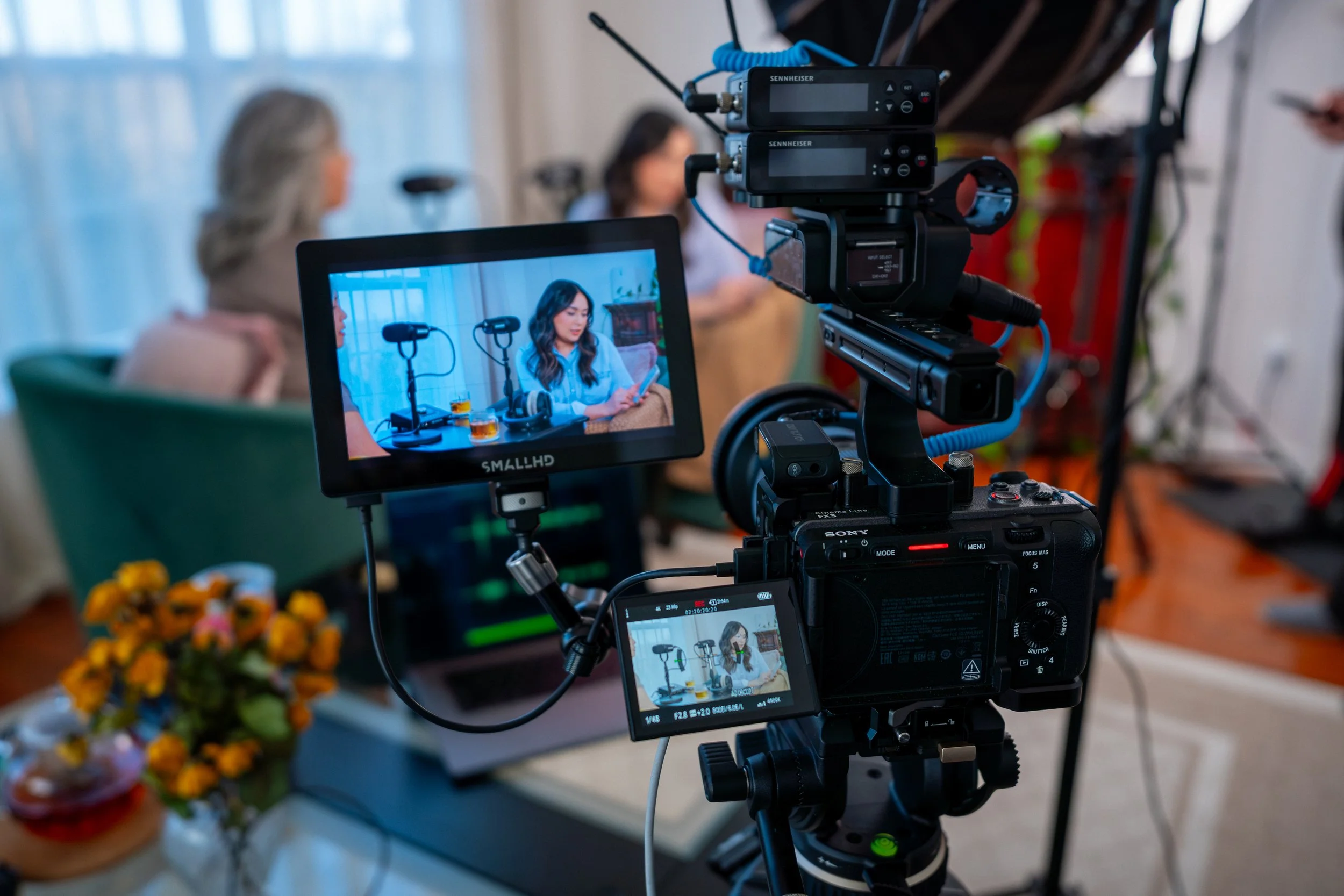 A professional camera setup filming a woman reading on a tablet during a video recording session in a cozy indoor setting.