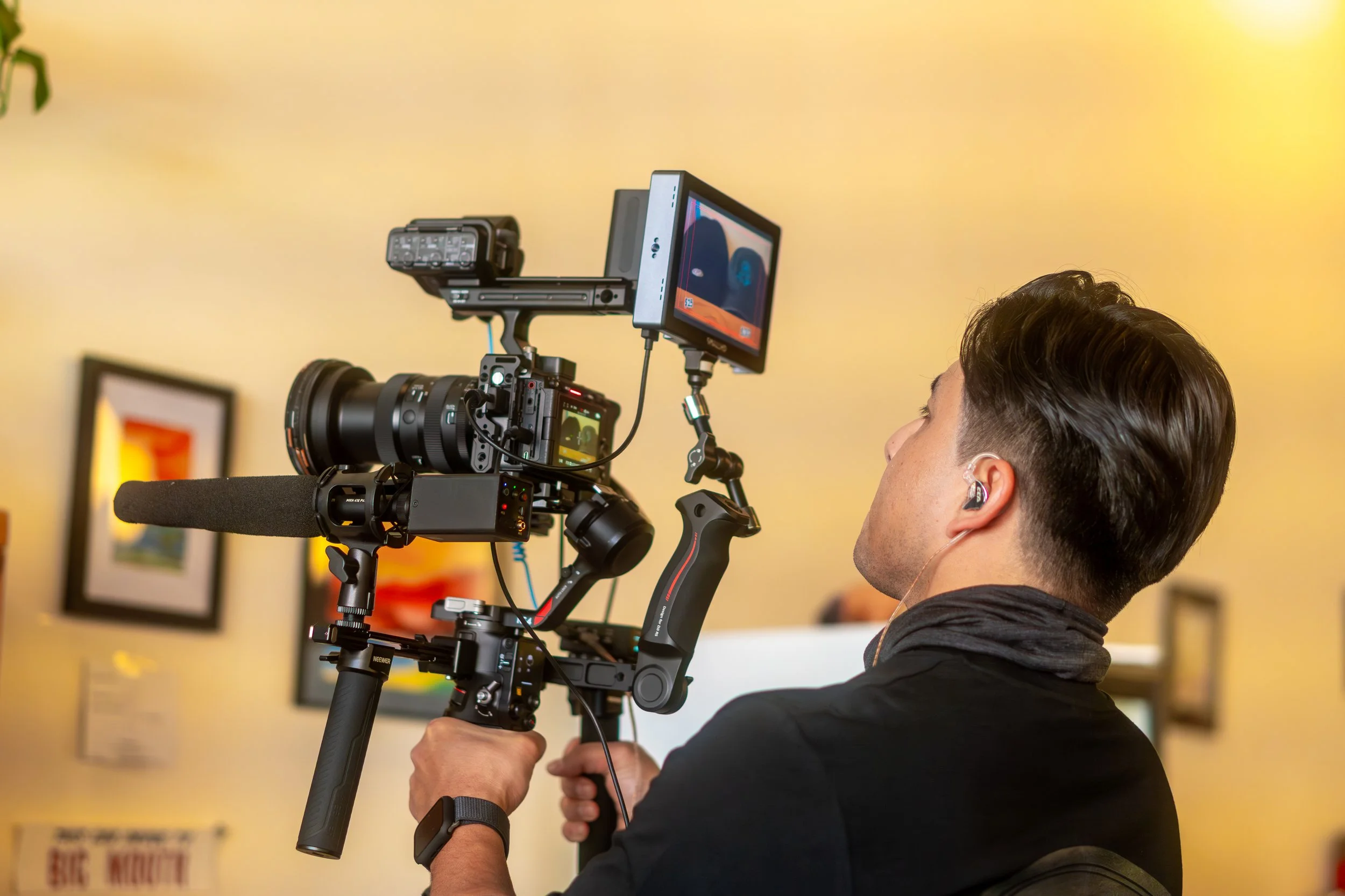 A man operating a professional video camera inside an art gallery.