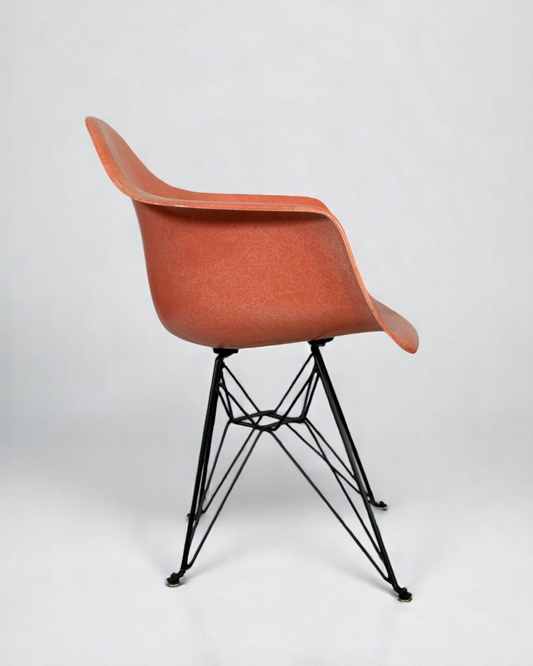 Modernica Case Study Furniture Arm Shell Eiffel chair, pre-owned, in color coral, with black metal base.