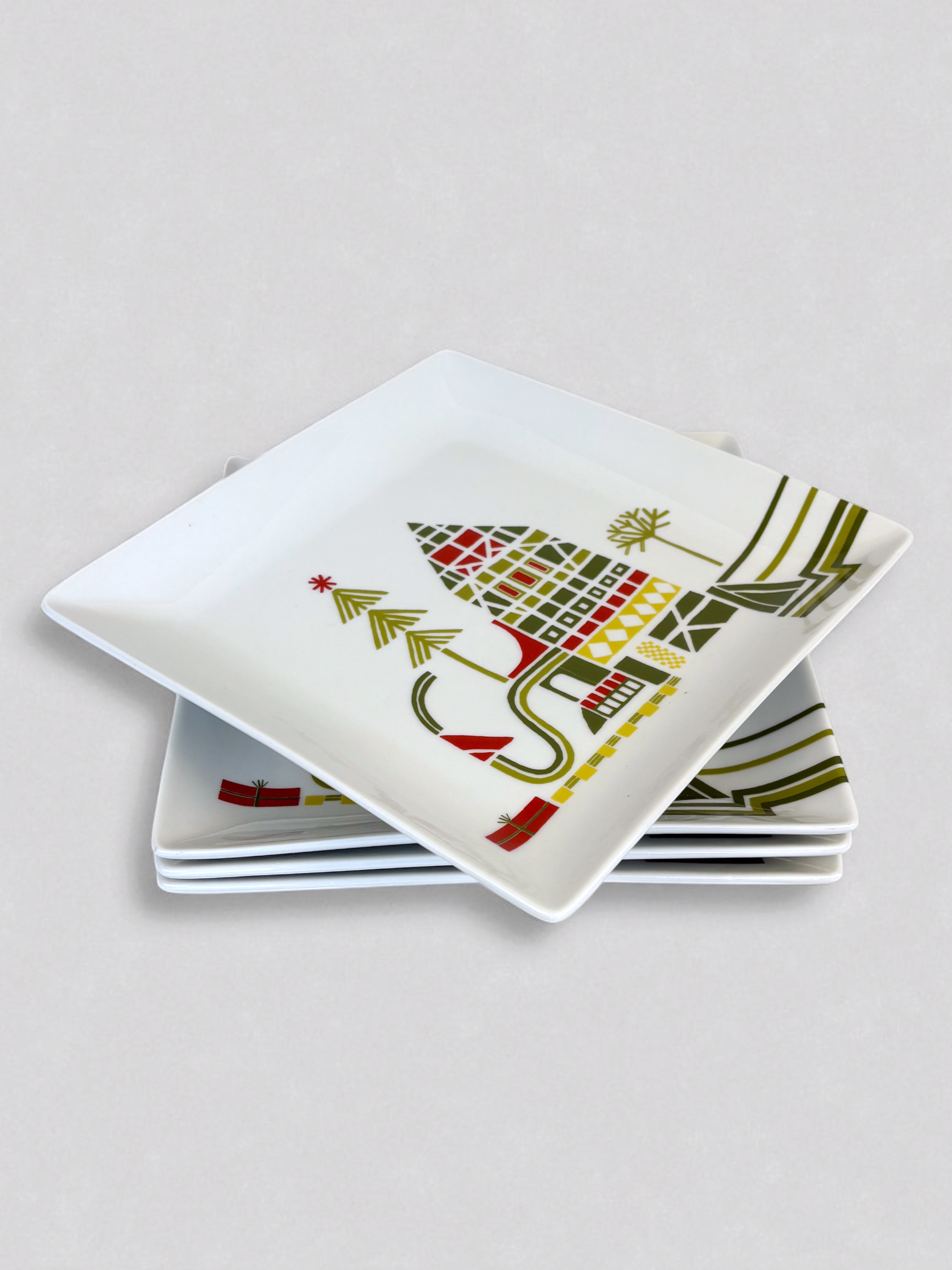 Set of Crate & Barrel Yule Town ceramic holiday plates and mugs by Julia Rothman, featuring whimsical village illustrations.