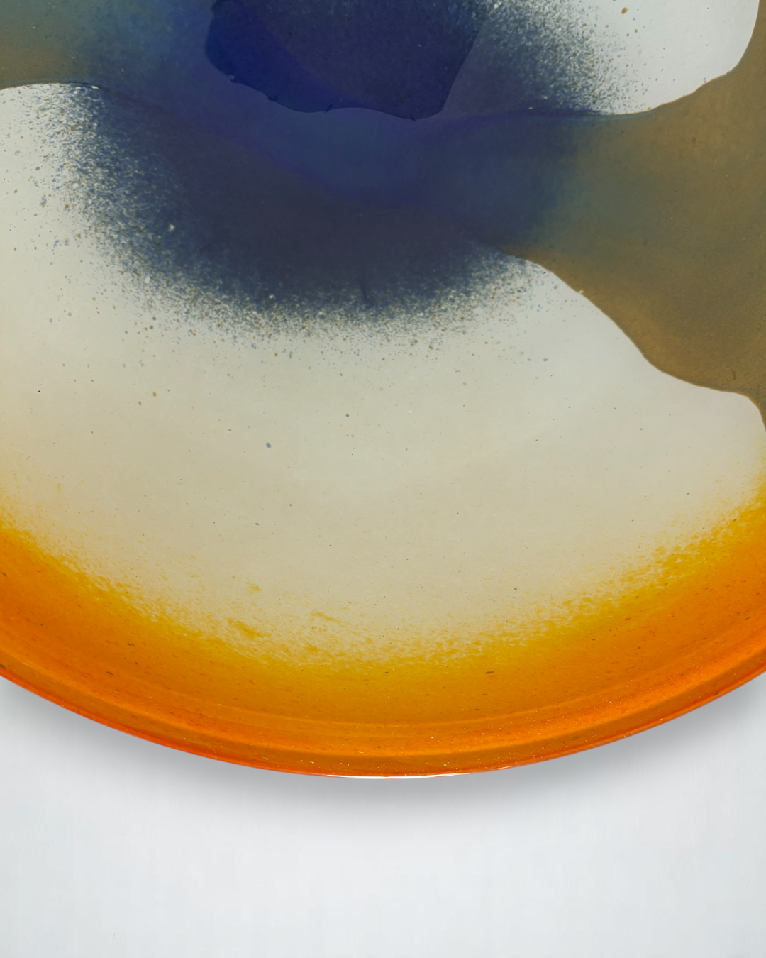 Image of handblown european art glass low bowl/plate. Colors are orange, white, navy and olive green produced in a style similar to nuvo Lithuania.