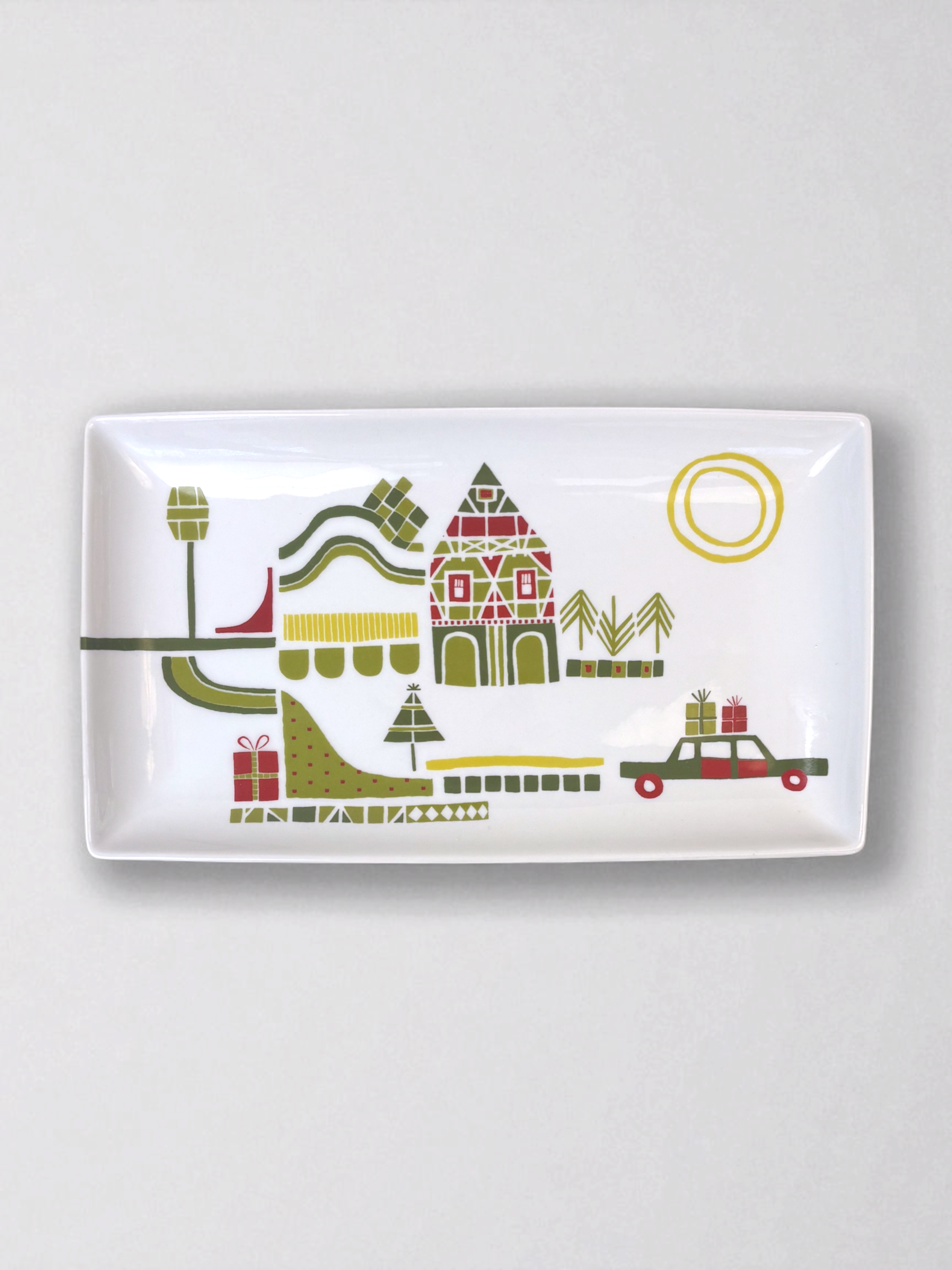 Set of Crate & Barrel Yule Town ceramic holiday plates and mugs by Julia Rothman, featuring whimsical village illustrations.
