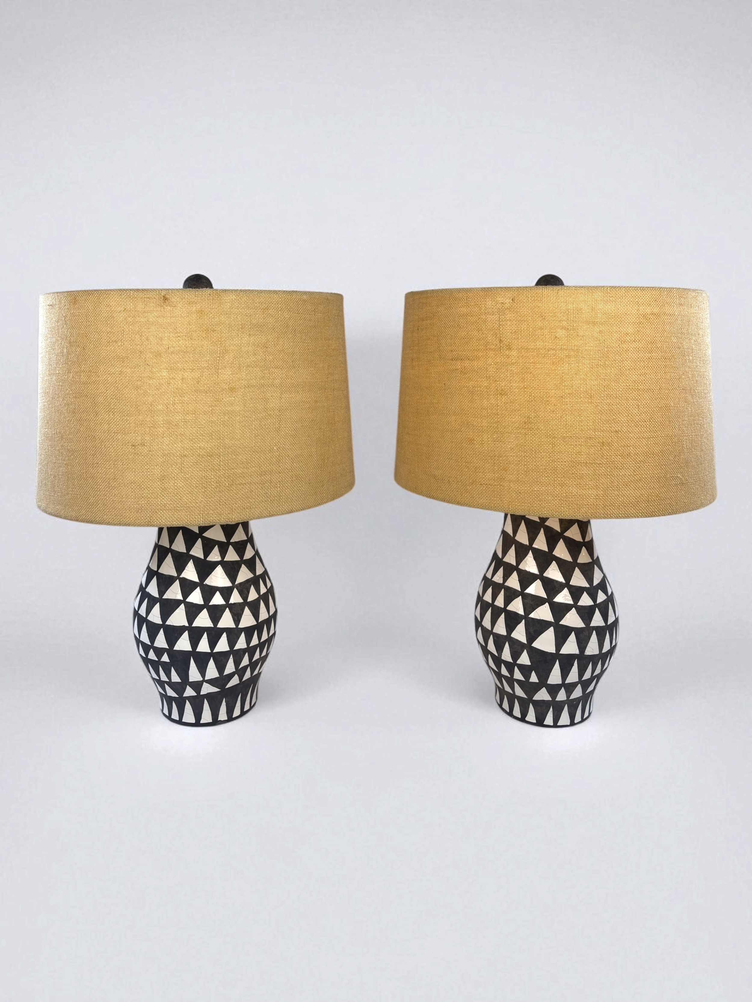 Image of two, pre-owned, black and white earthenware table lamps with jute lampshades.